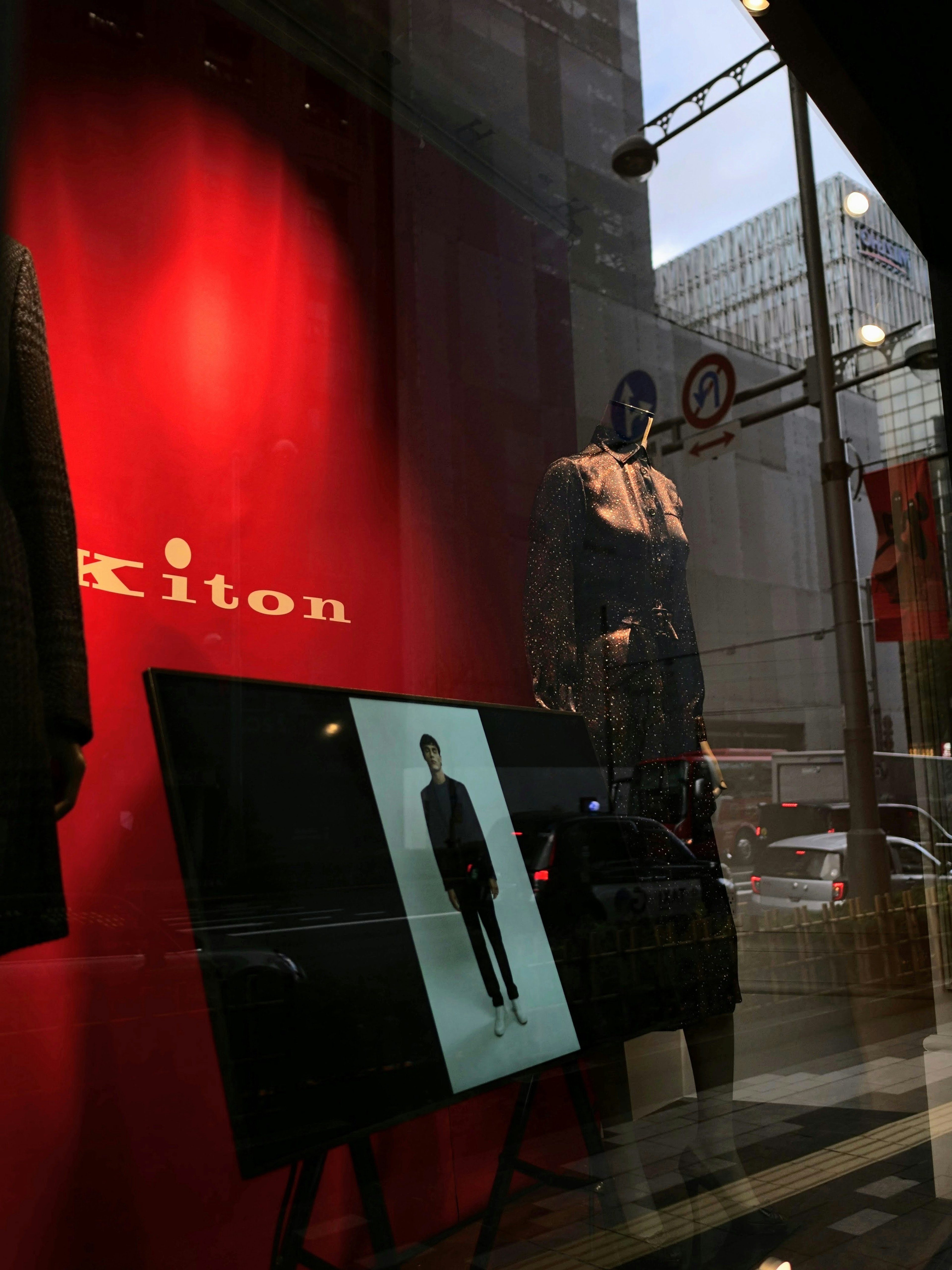 Vetrina di Kiton che espone articoli di moda con sfondo rosso