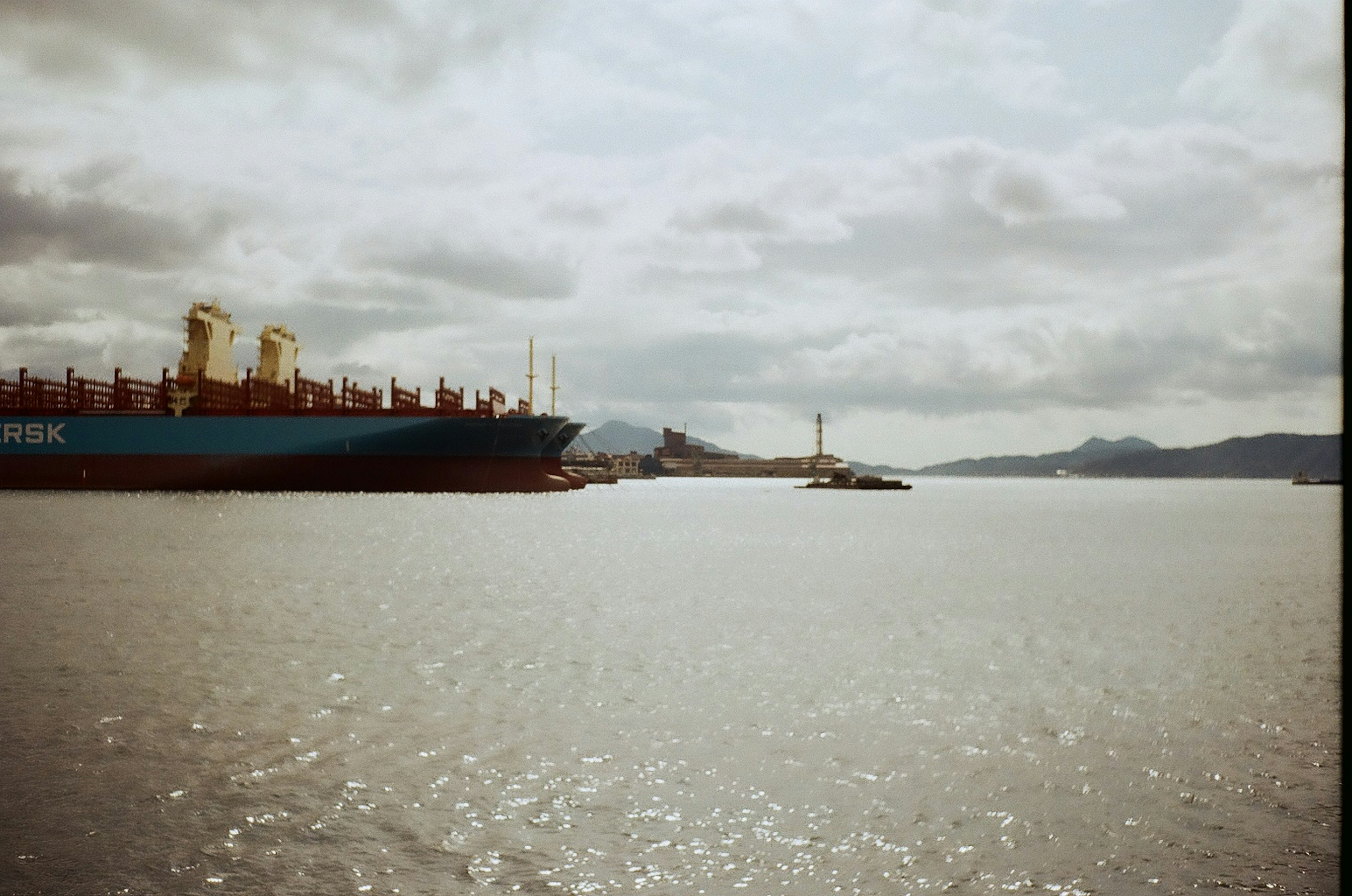 Cargo ship on the water with a lighthouse in the background