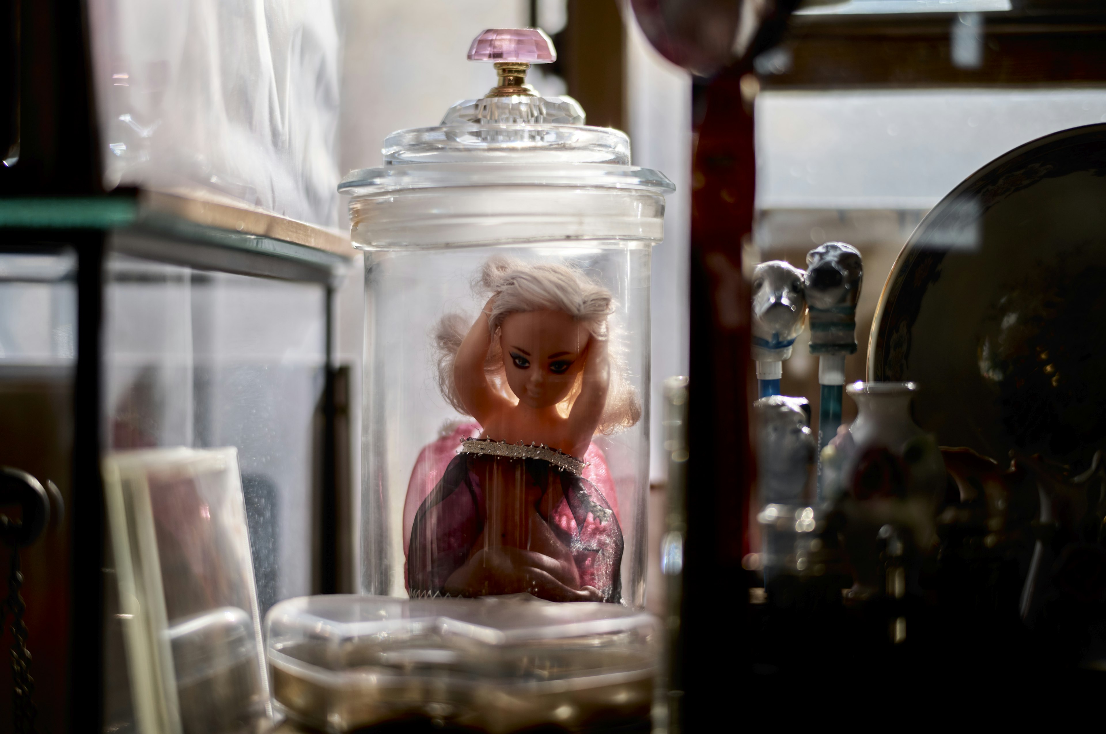 An antique doll inside a glass case surrounded by various collectibles