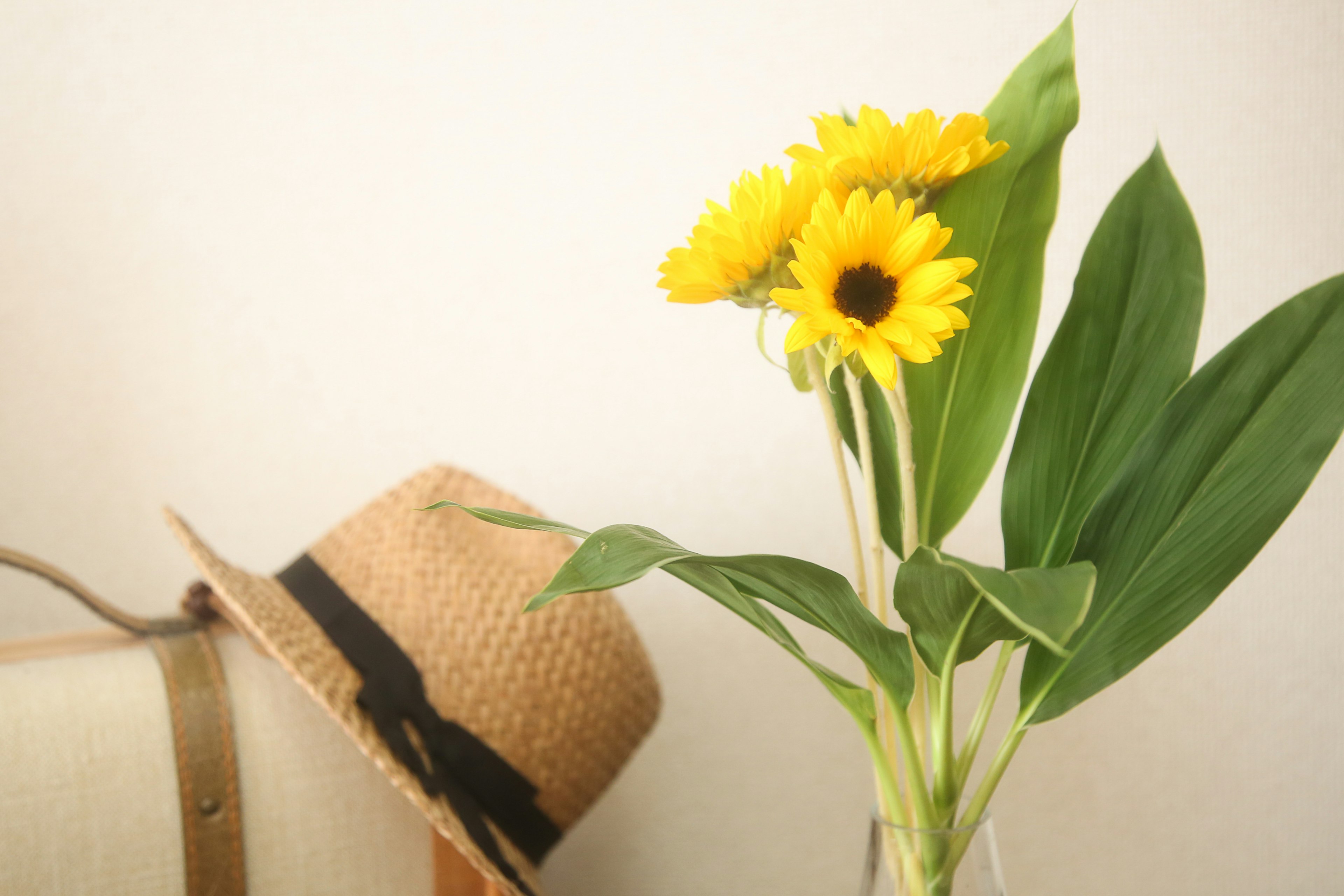 A straw hat and a bouquet of sunflowers in a simple interior setting