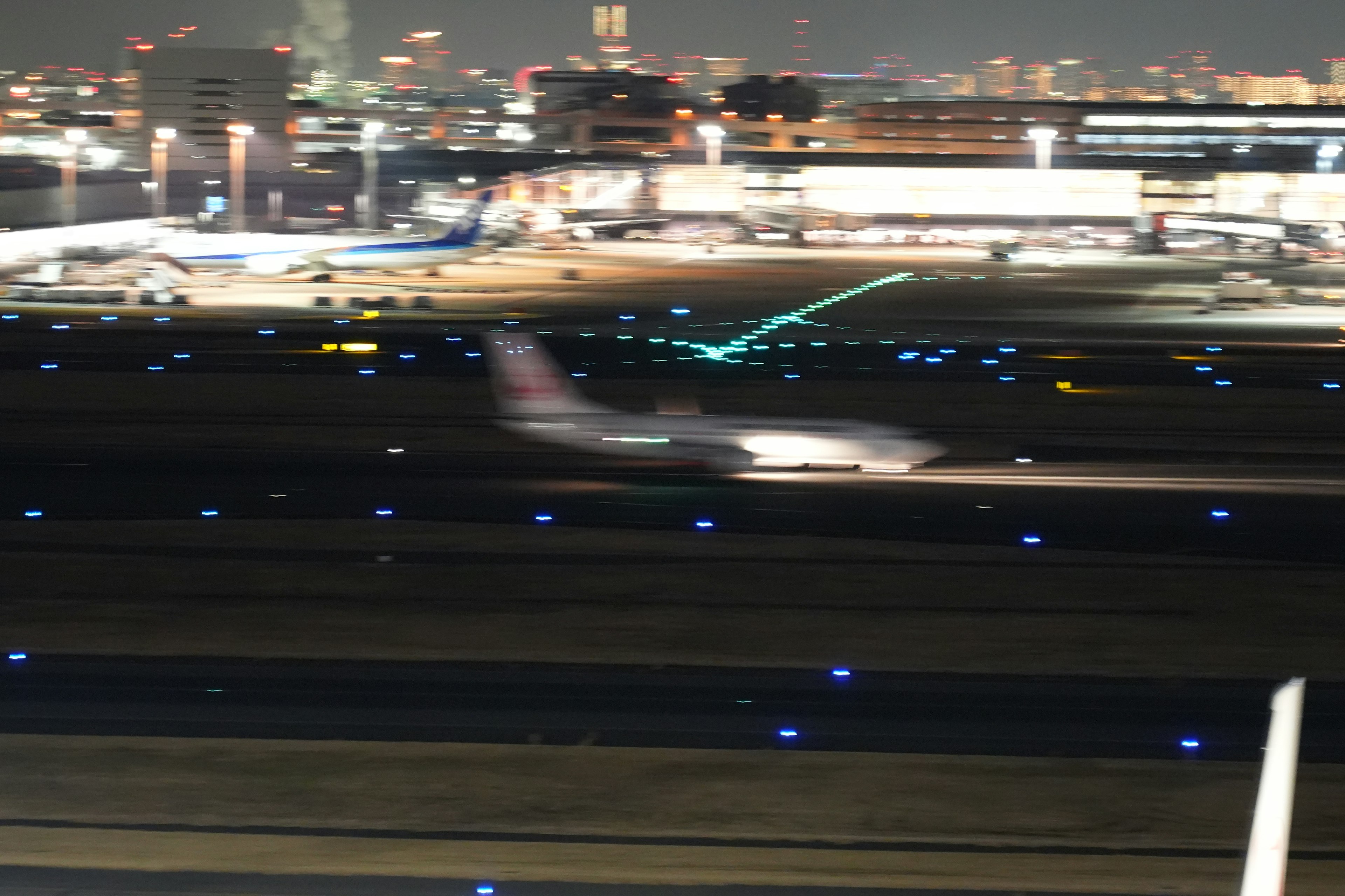 夜の空港で離陸する飛行機と周囲の都市の明かり