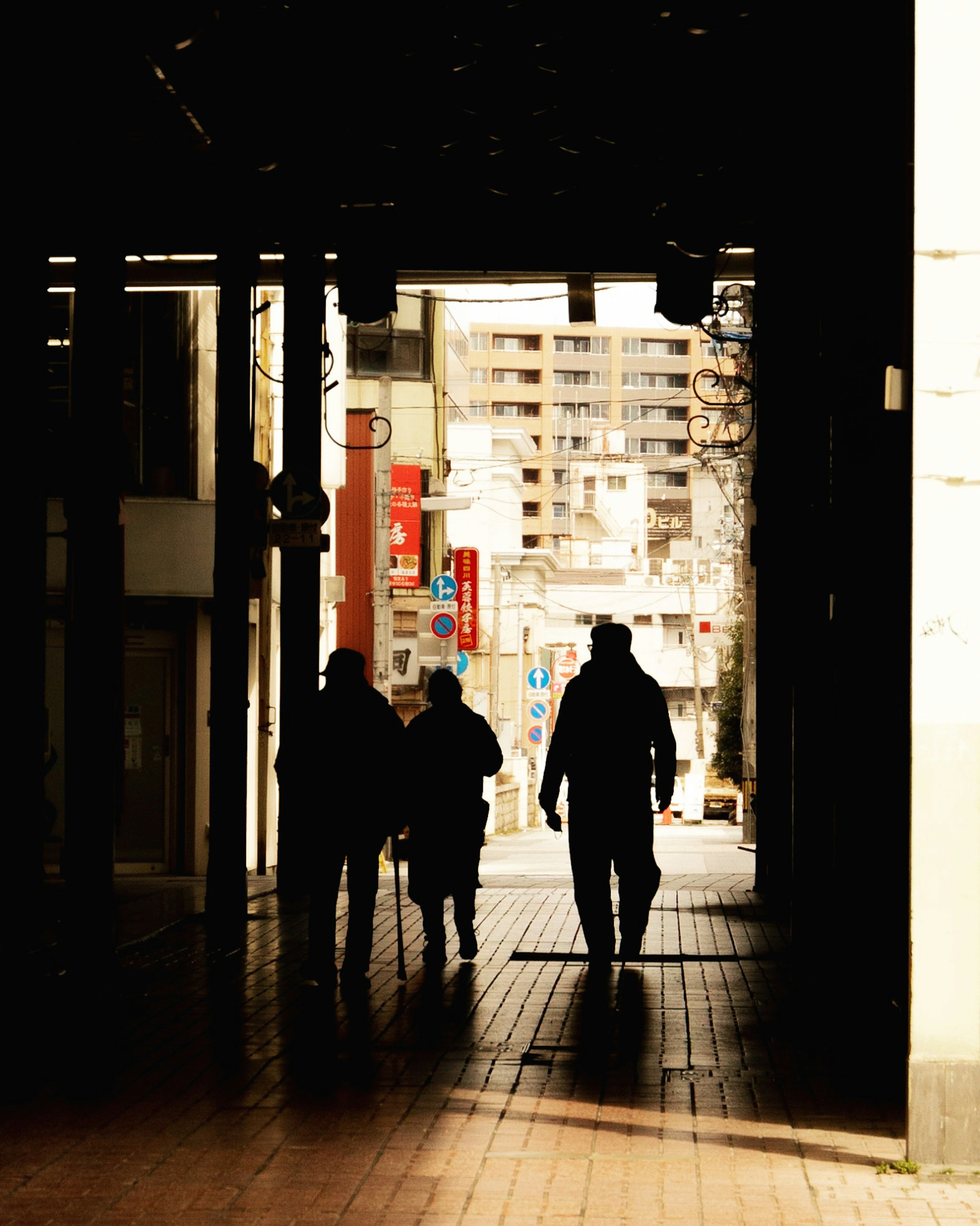 Silhouettes of people walking through a dark alley