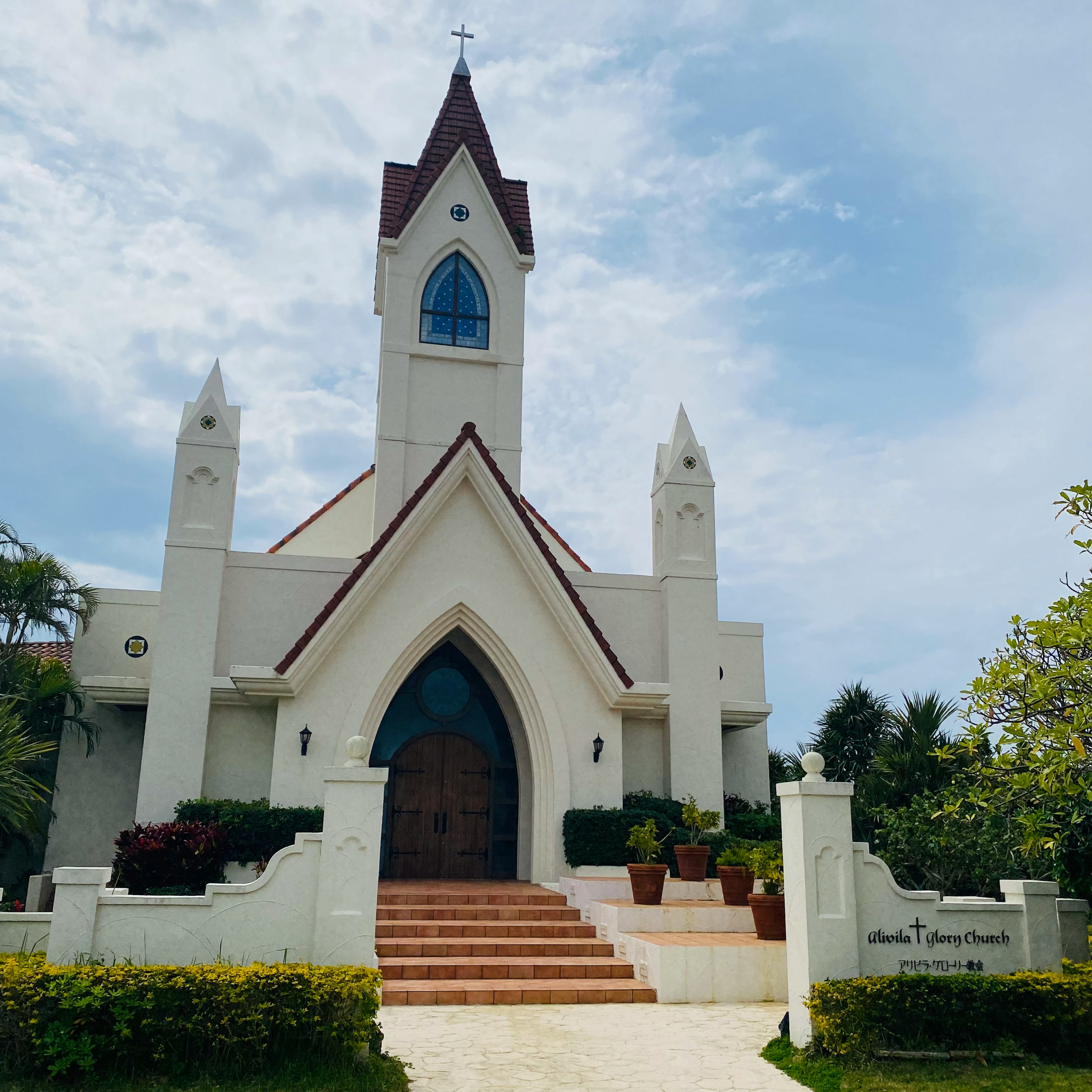 โบสถ์สีขาวที่สวยงามมีประตูโค้งขนาดใหญ่และหน้าต่างสีน้ำเงินที่โดดเด่น