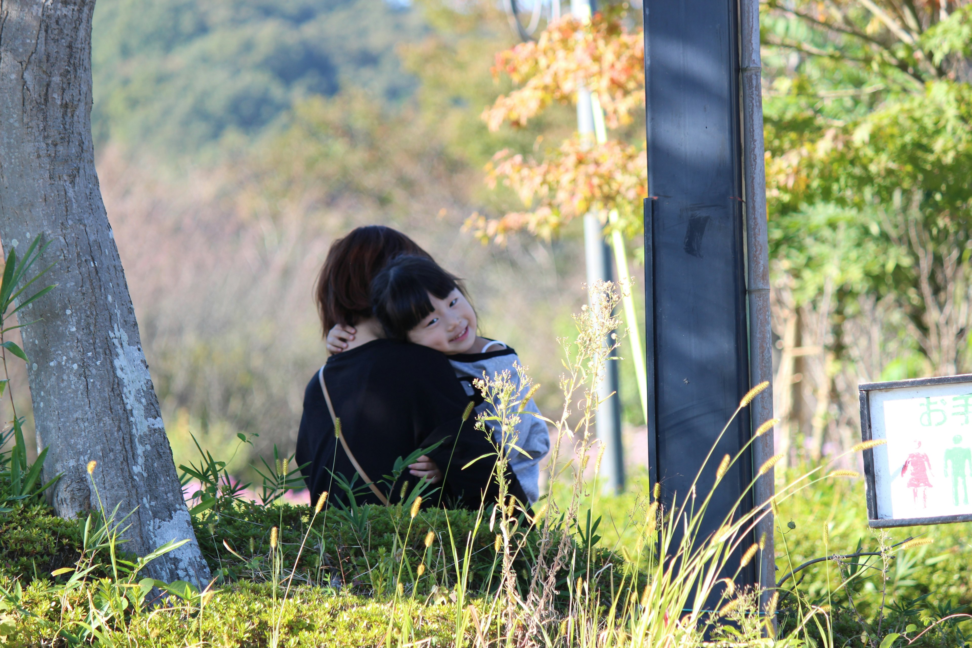 Dos mujeres abrazándose en un parque césped verde y árboles de fondo