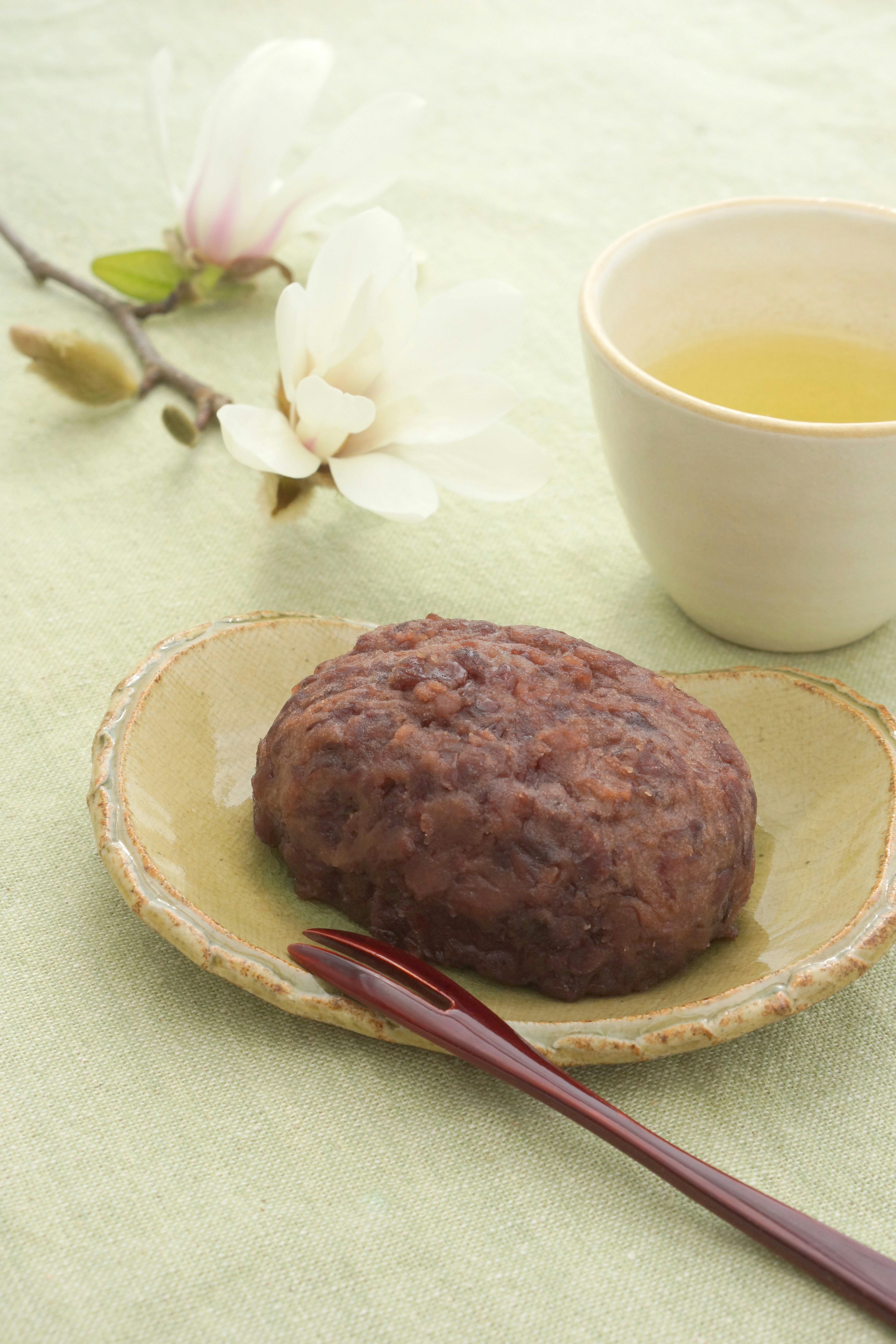 緑色のテーブルクロスの上に置かれたあんこ餅とお茶のセット