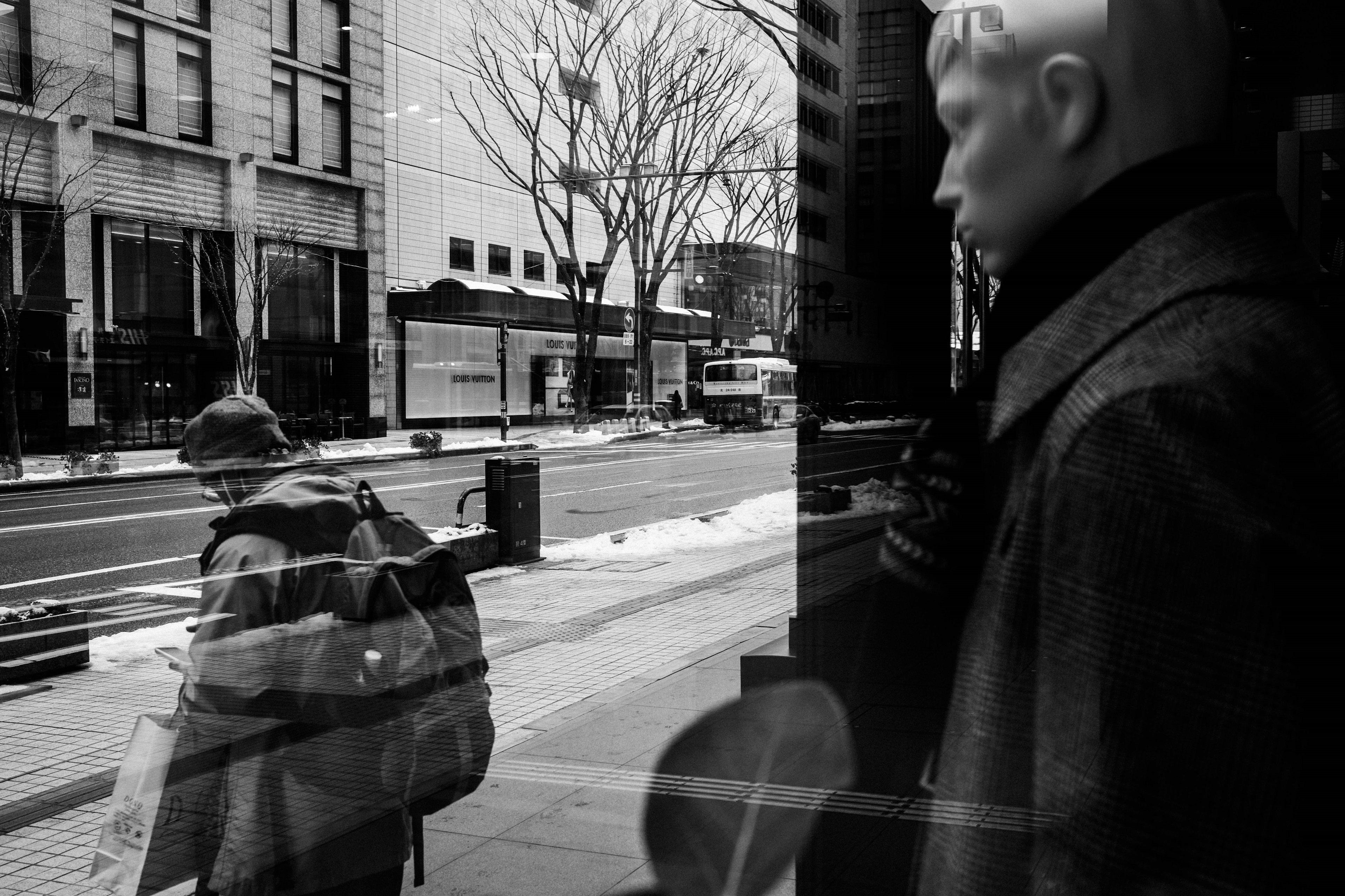 Cityscape reflection with a mannequin and passerby seen through a window