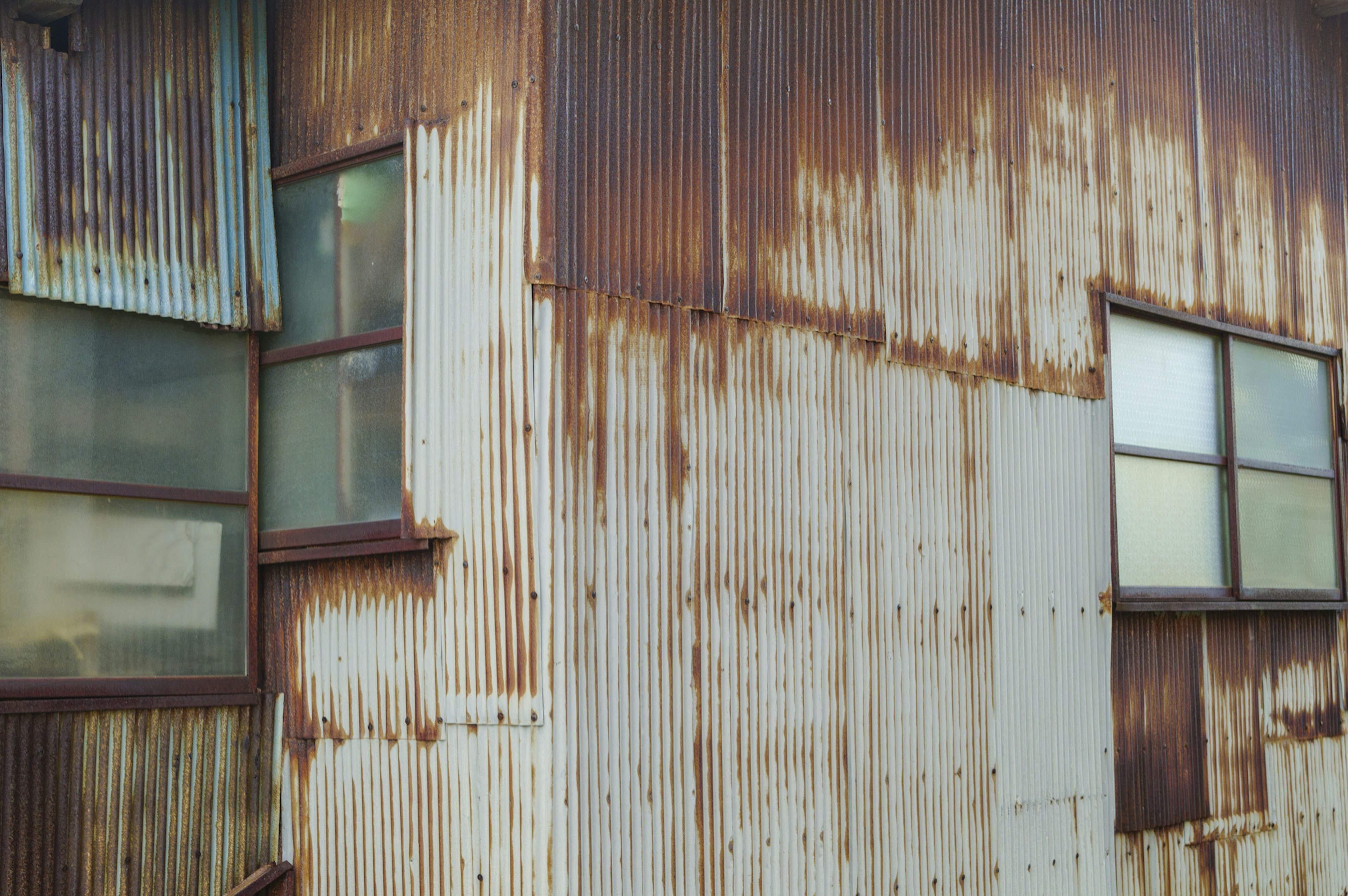 Close-up of an old building with rusted metal walls and windows