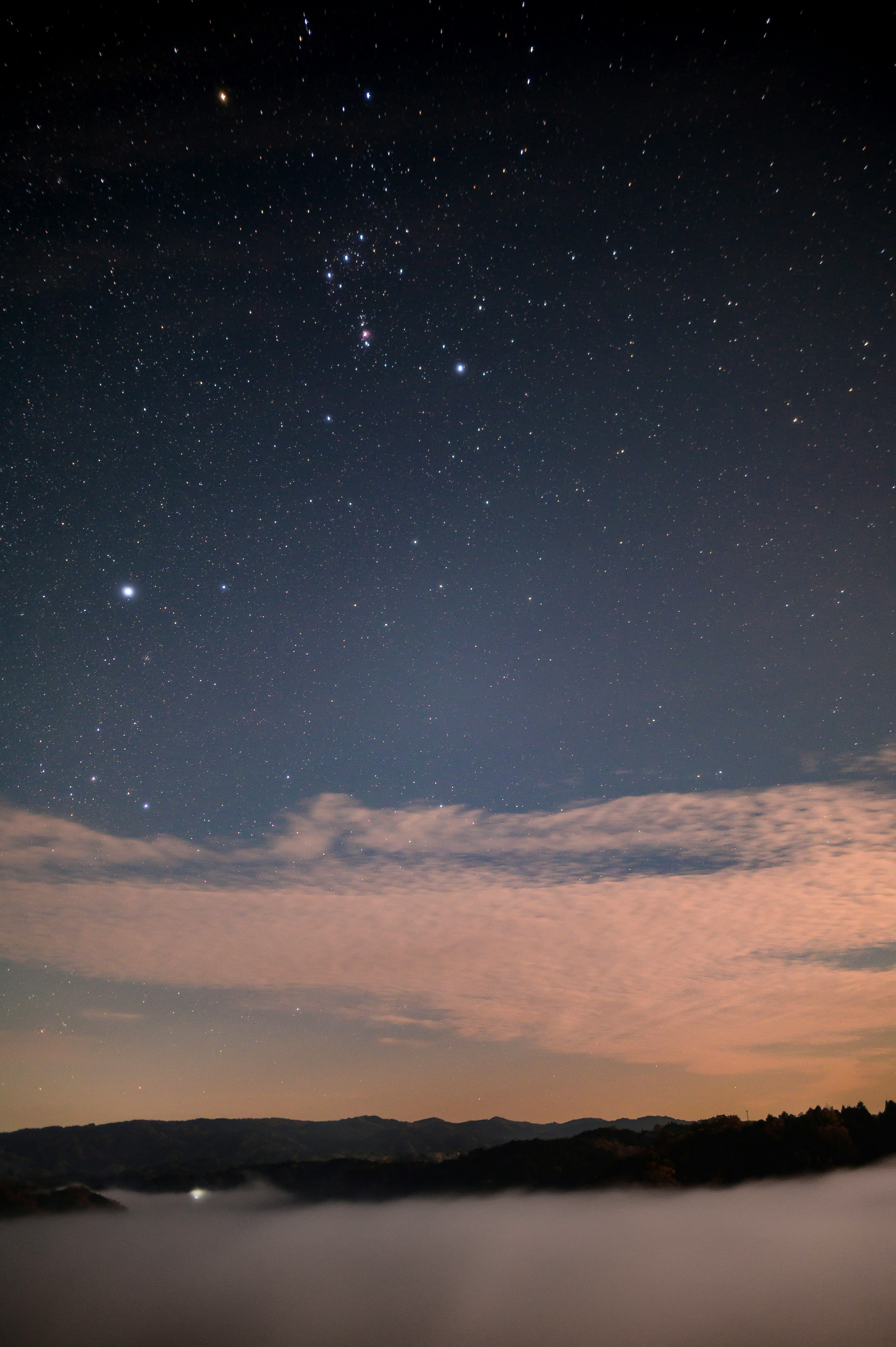 Cielo estrellado con nubes visibles sobre un paisaje