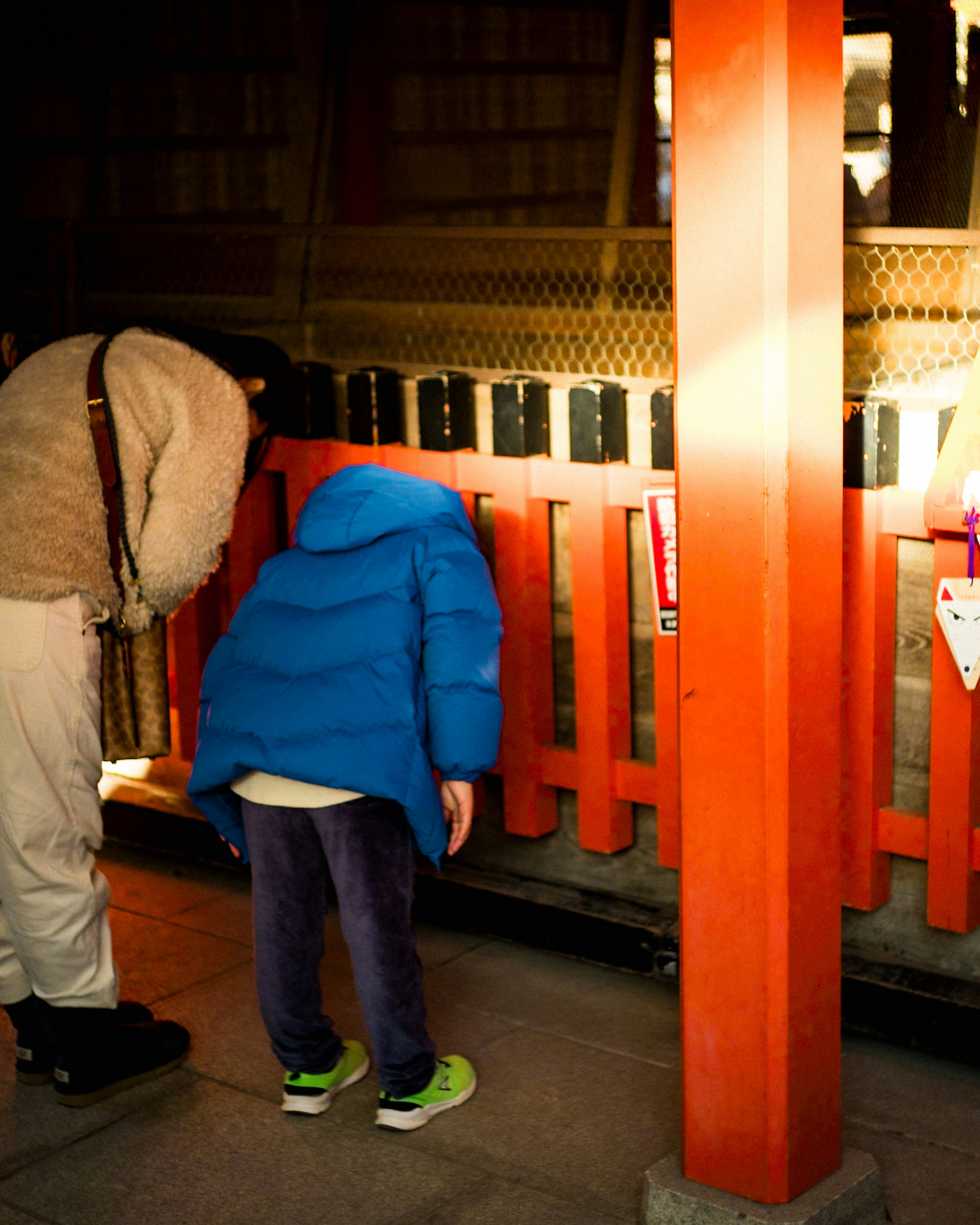 子供と大人が赤い柵を覗き込んでいるシーン