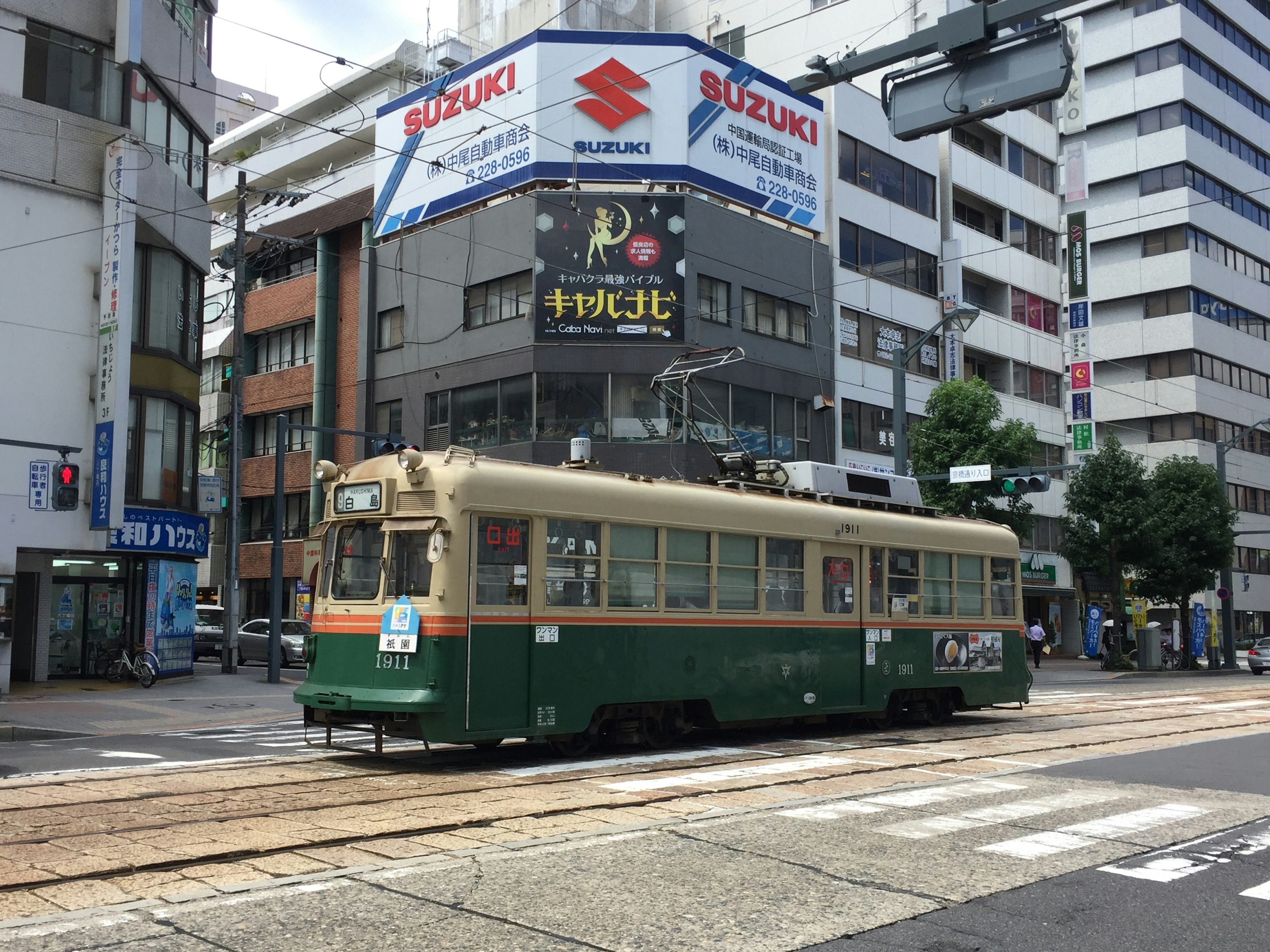 Green and cream streetcar crossing an urban intersection