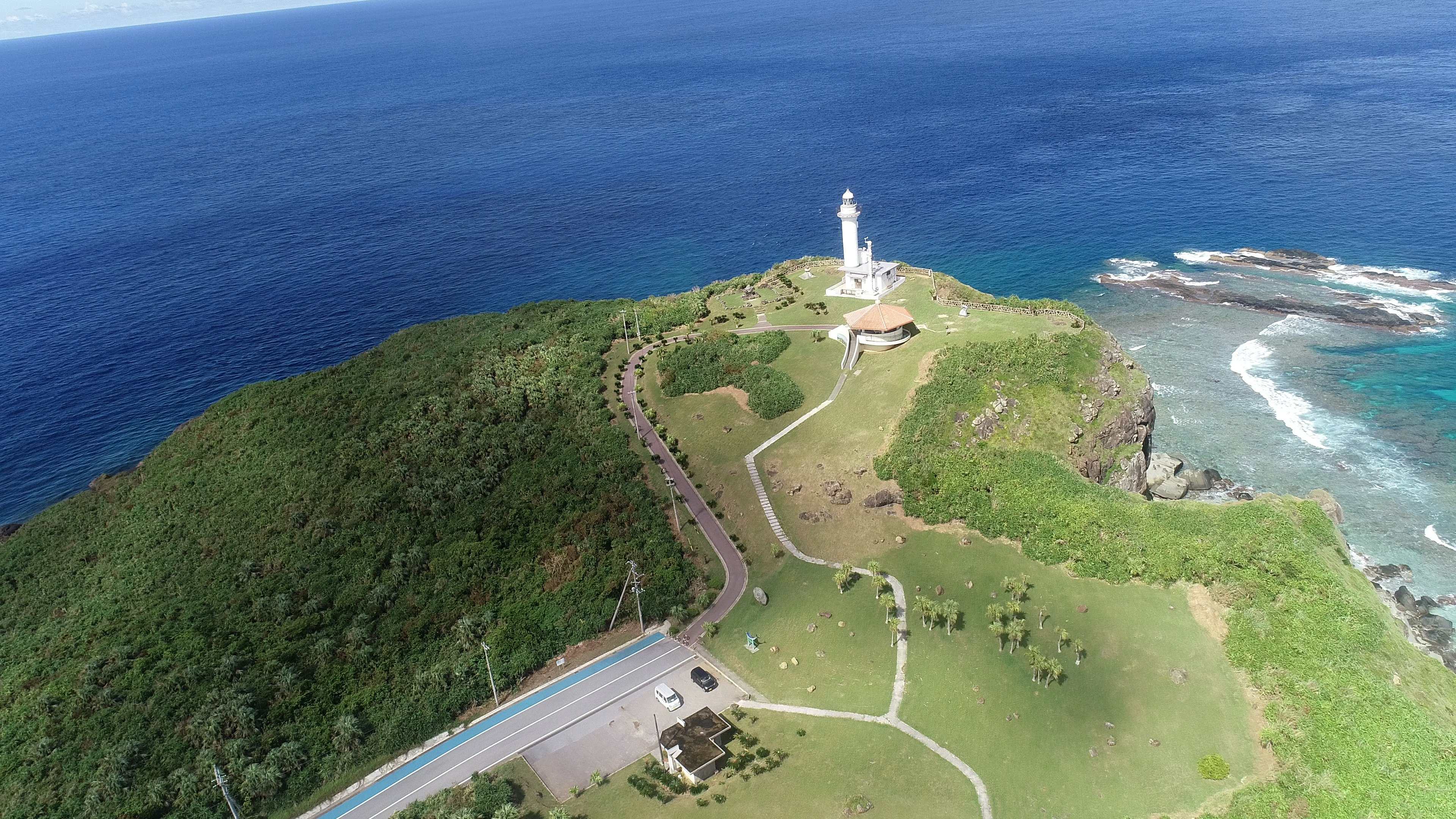 Vista aerea di un faro su una collina verde che sovrasta l'oceano