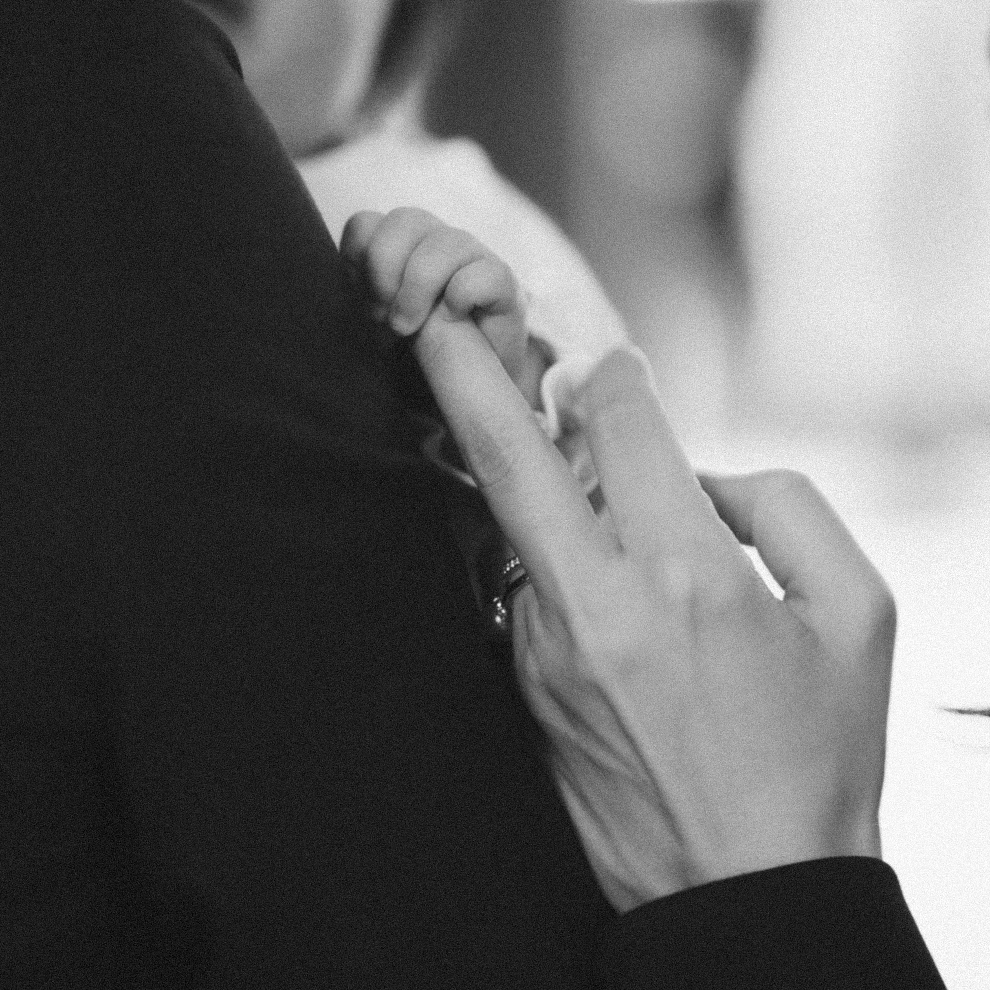 A tender moment of a child's hand grasping an adult's finger showcasing a ring