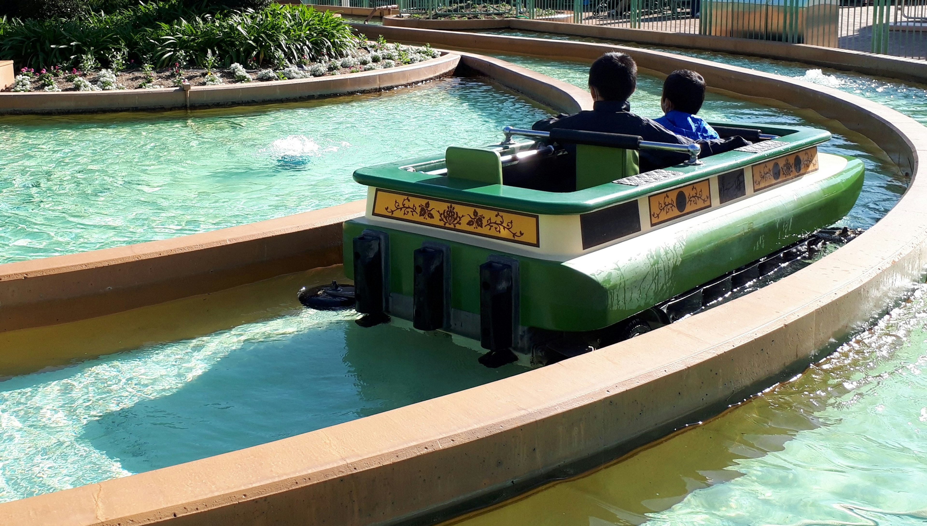 Two children in a green boat navigating a waterway