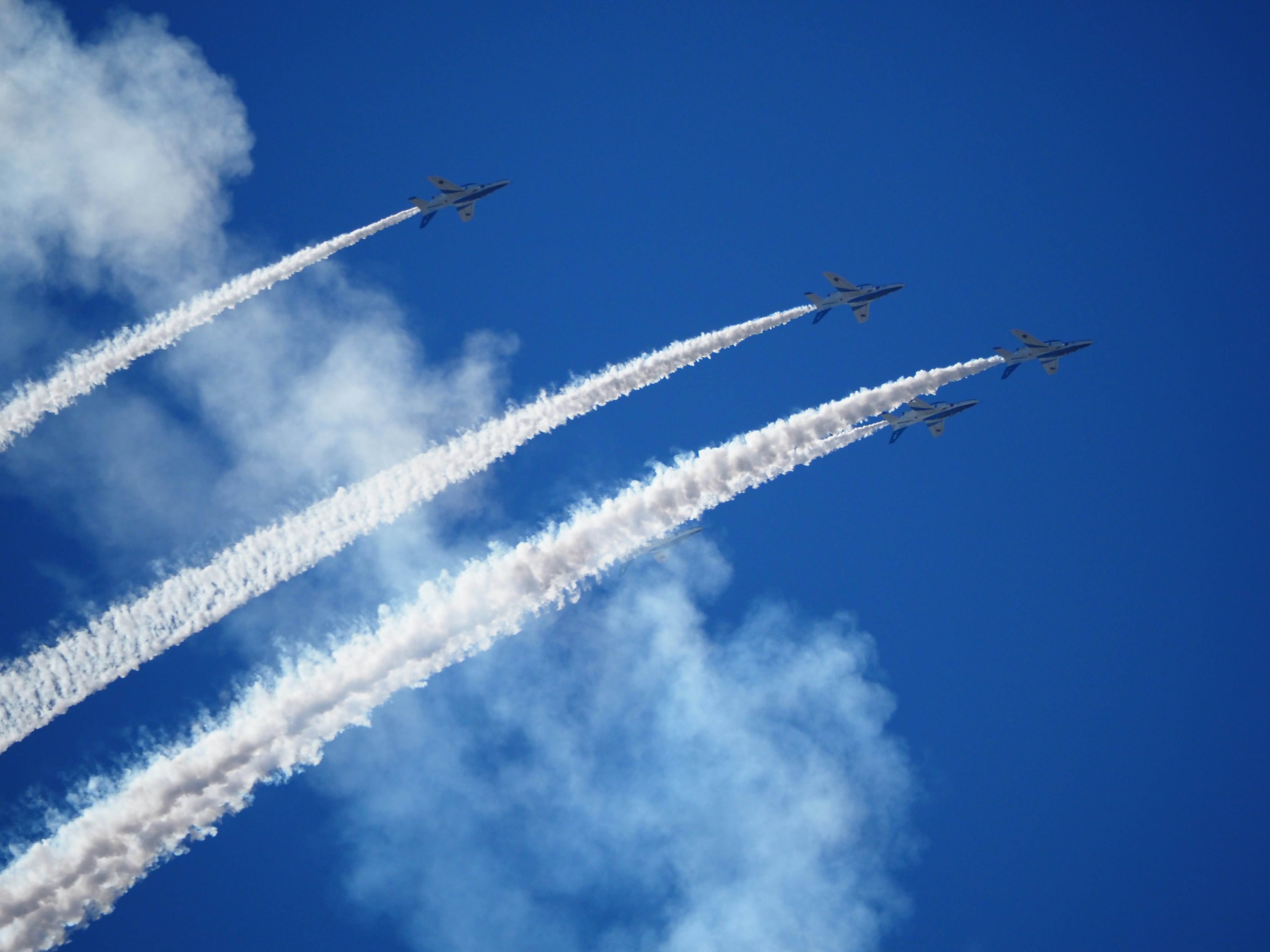 Vier Flugzeuge fliegen in einem blauen Himmel und hinterlassen weiße Kondensstreifen