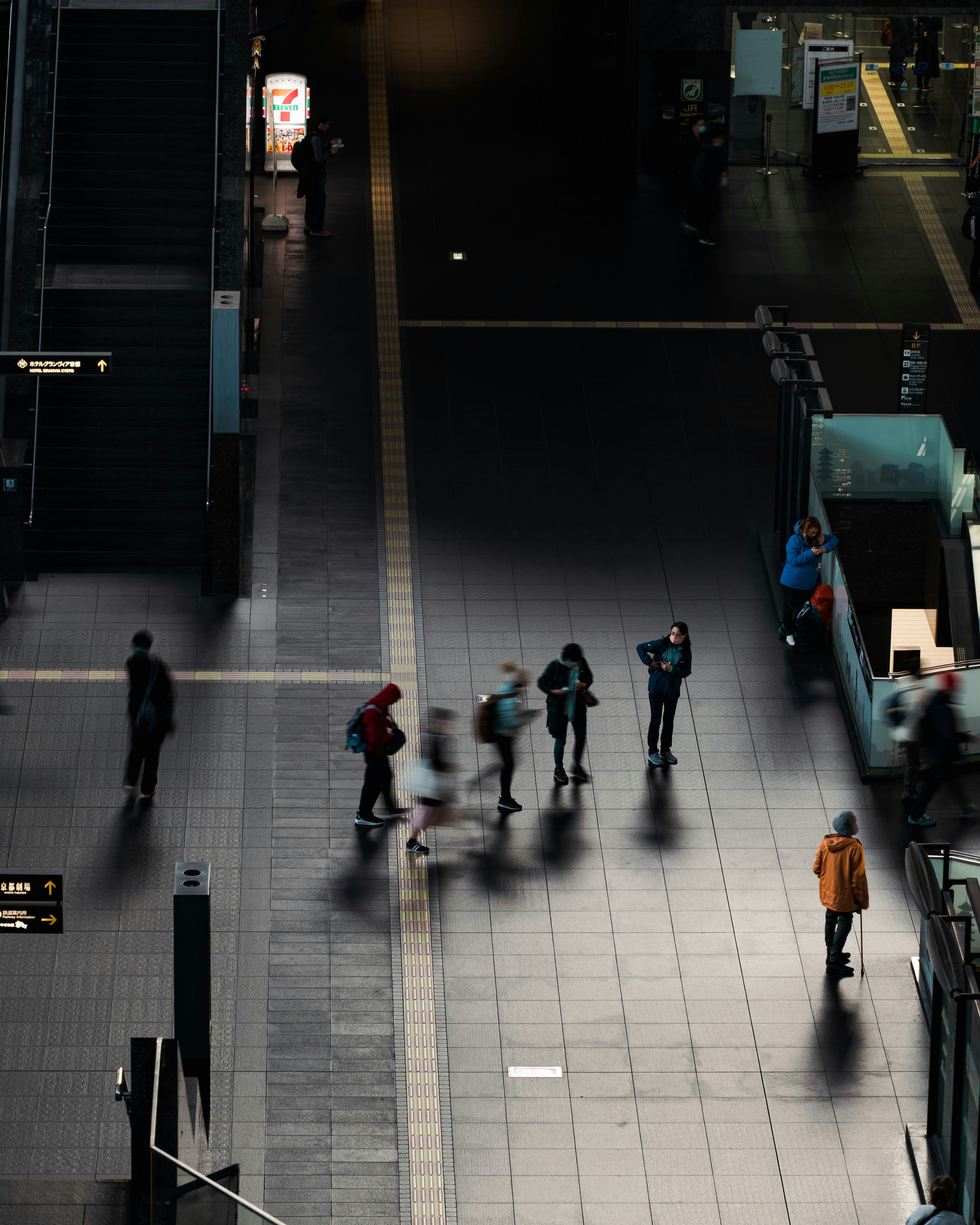 Foto en ángulo alto de personas moviéndose en una estación Sombras proyectadas en un suelo oscuro