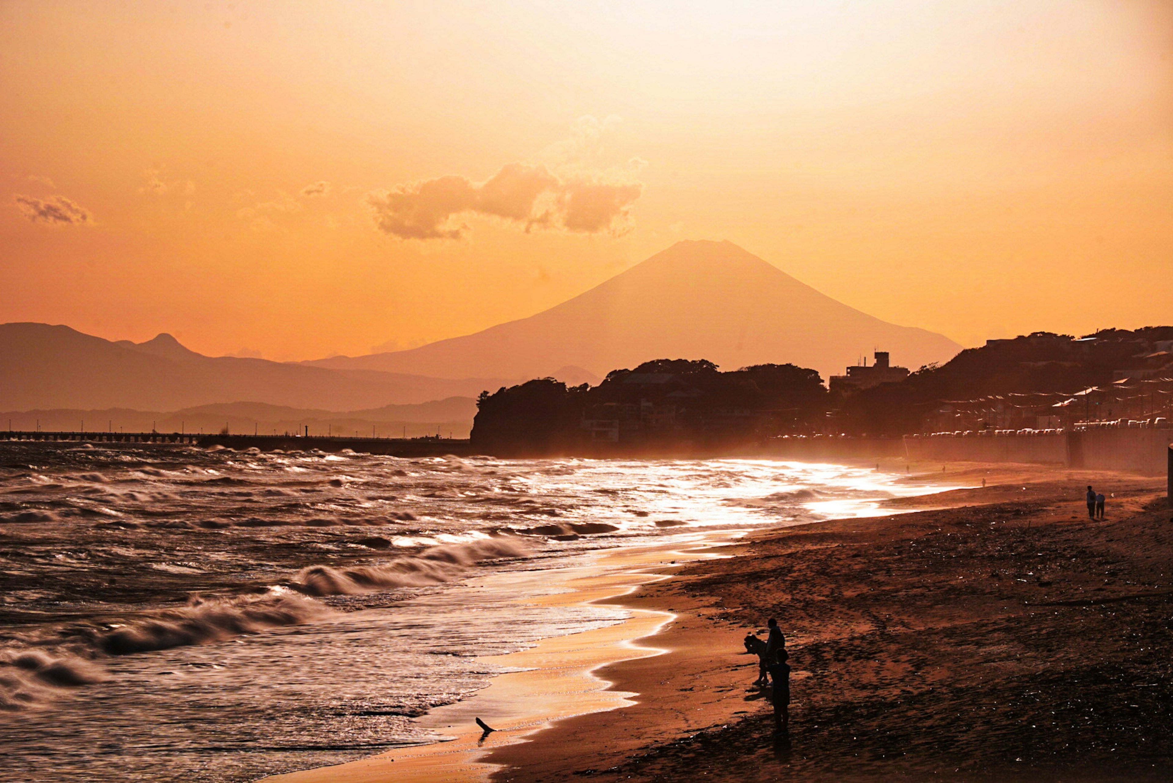 Playa al atardecer con silueta del Monte Fuji