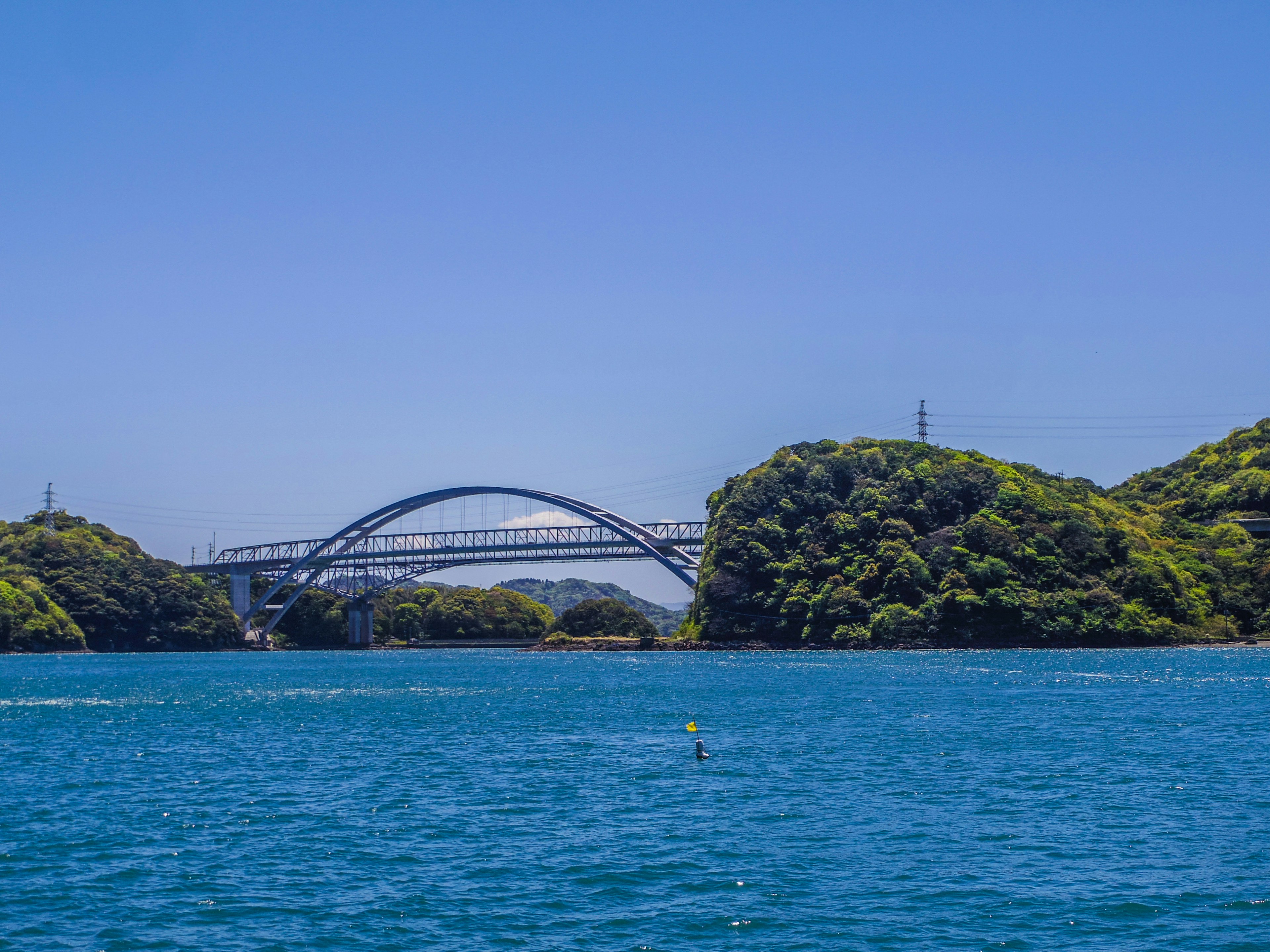 一座美麗的拱形橋橫跨在藍色海面與綠色島嶼之間