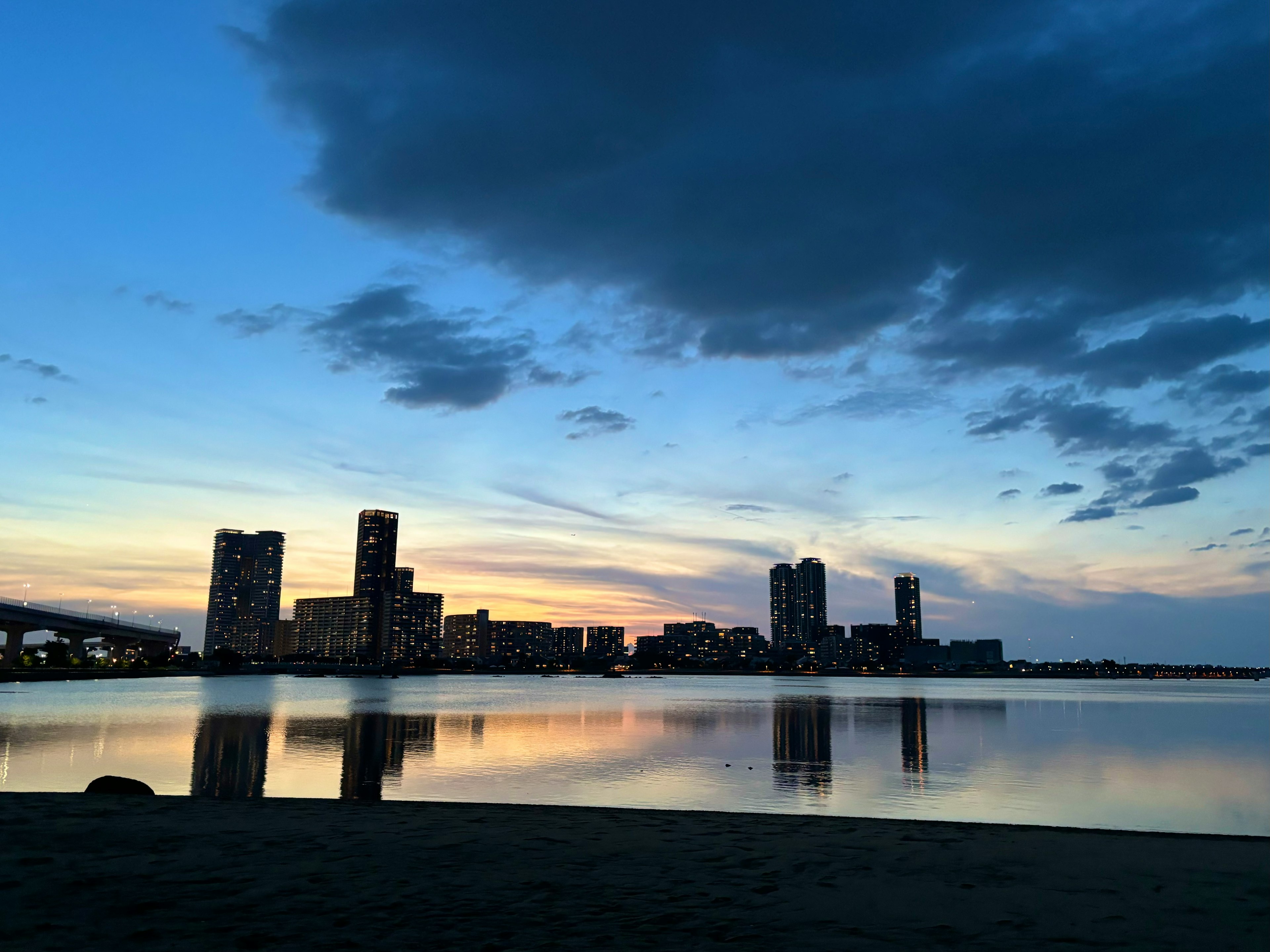 美しい夕焼けの中の都市のスカイラインと水面に映る反射