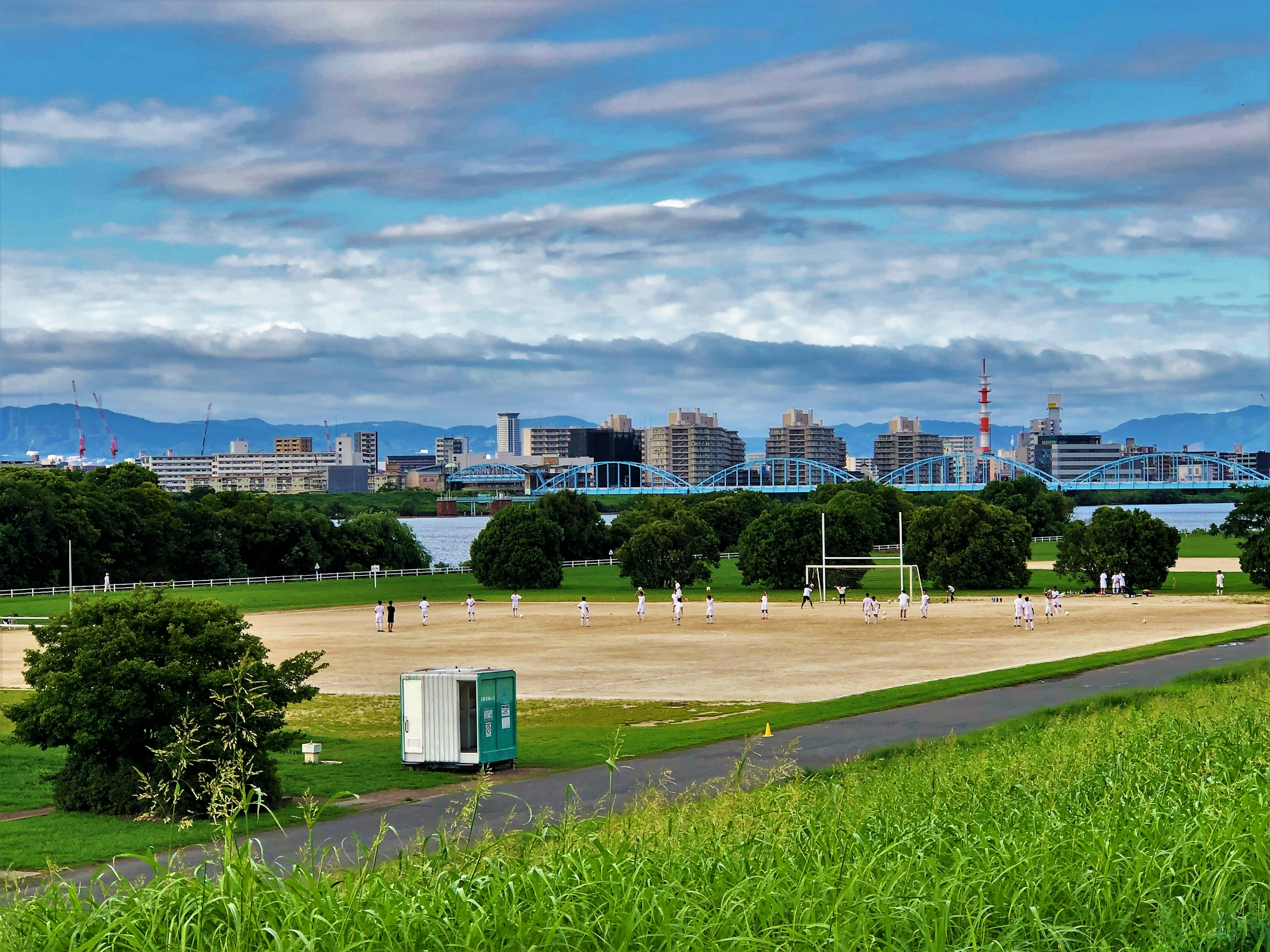 Amplio campo de fútbol con el horizonte urbano y montañas de fondo