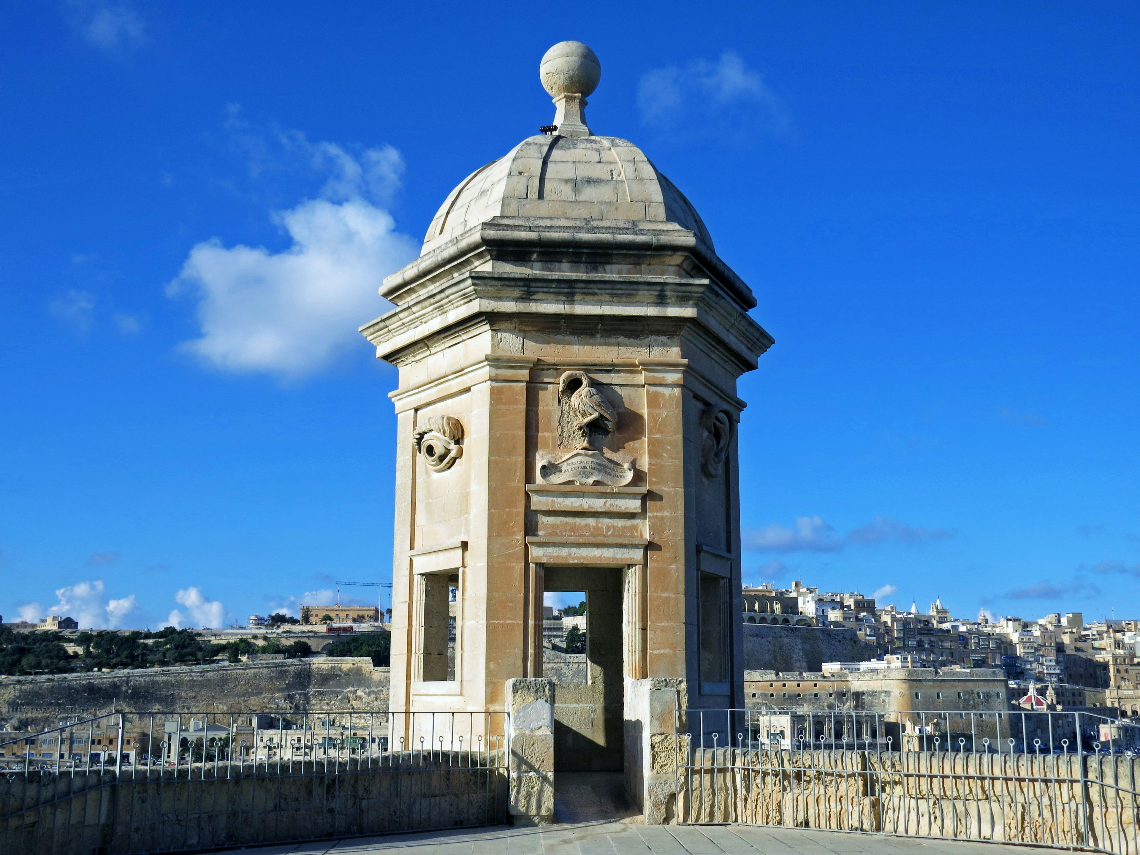 Historical tower under a blue sky with visible surrounding landscape