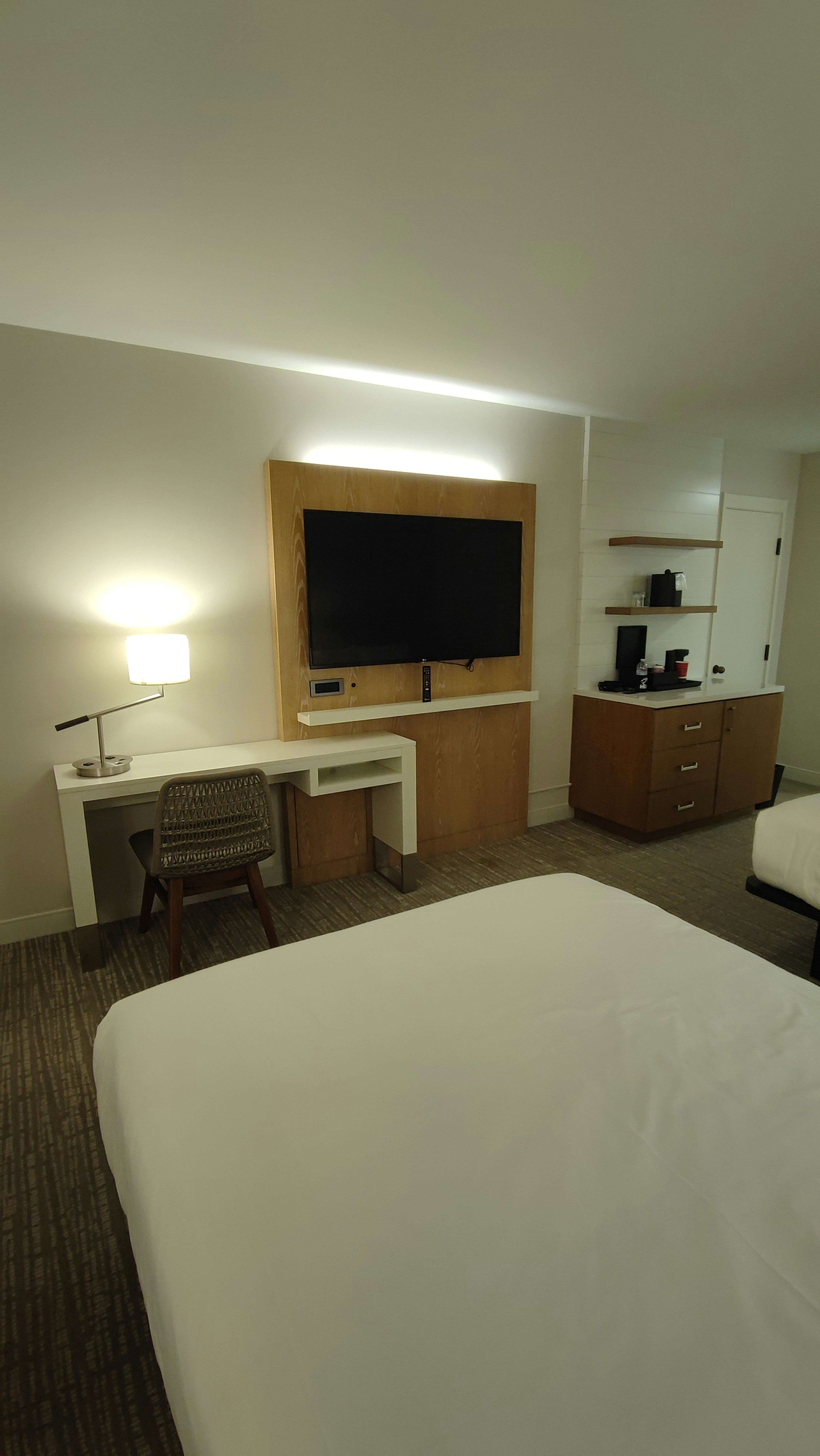 Simple modern hotel room featuring a desk chair and wall-mounted TV