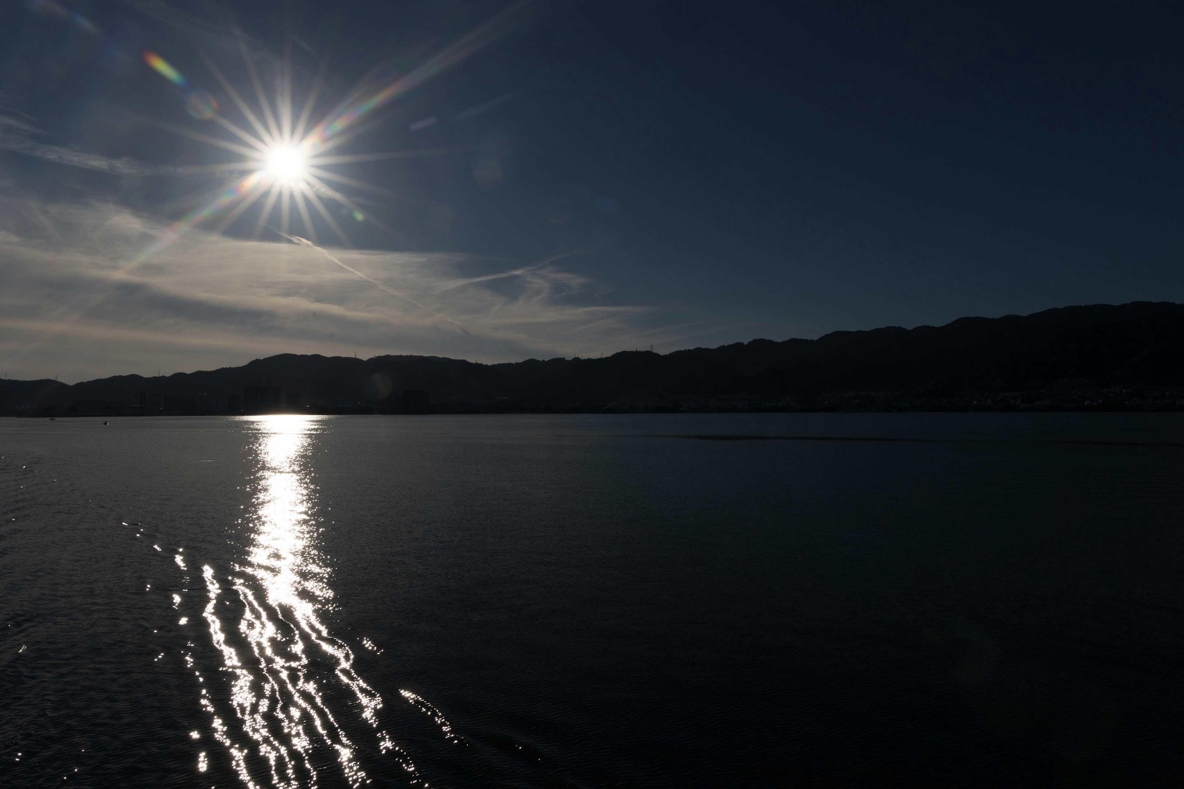 Sonne, die über dem Wasser mit Reflexionen scheint