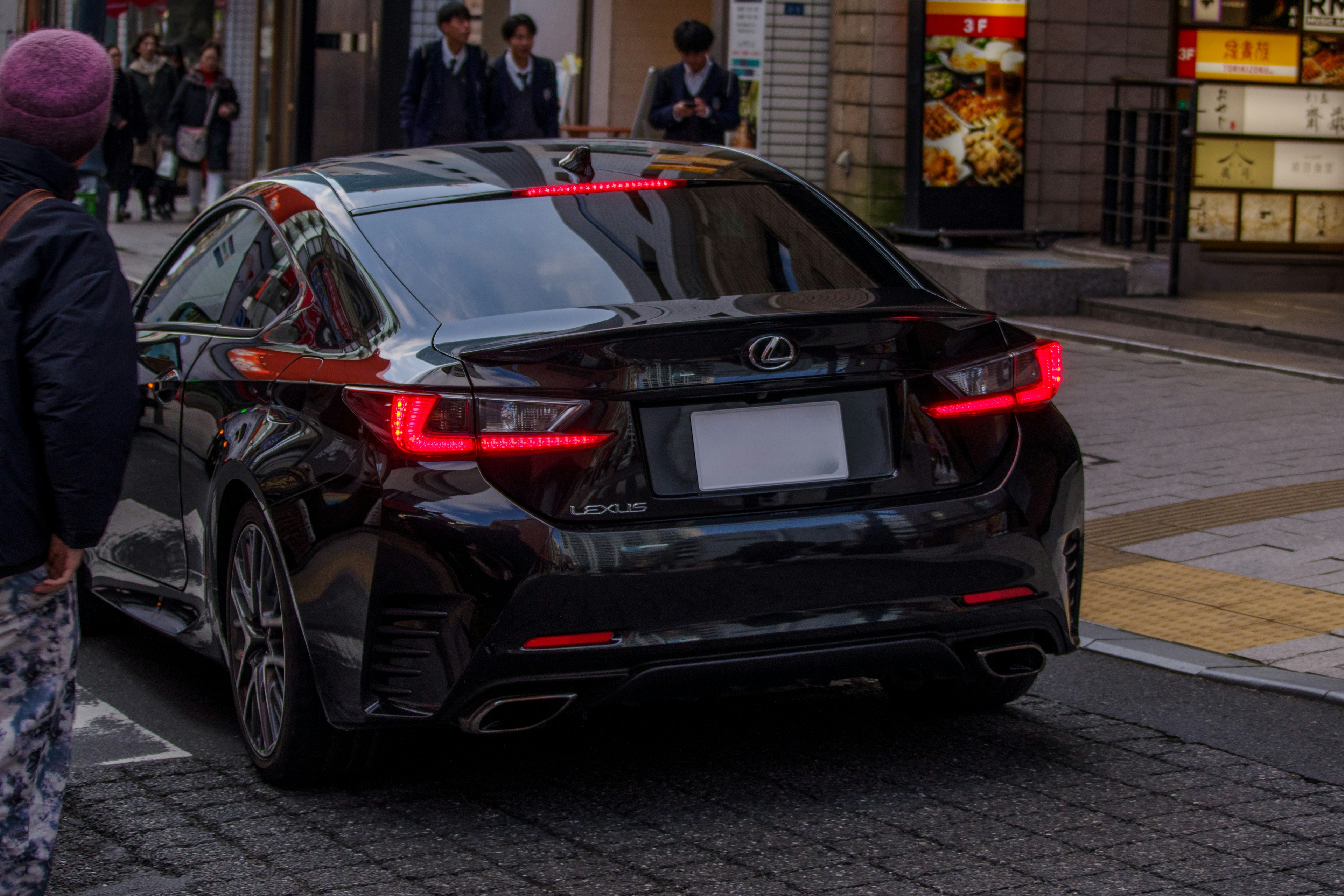 Tampilan belakang Lexus hitam yang diparkir di jalan kota