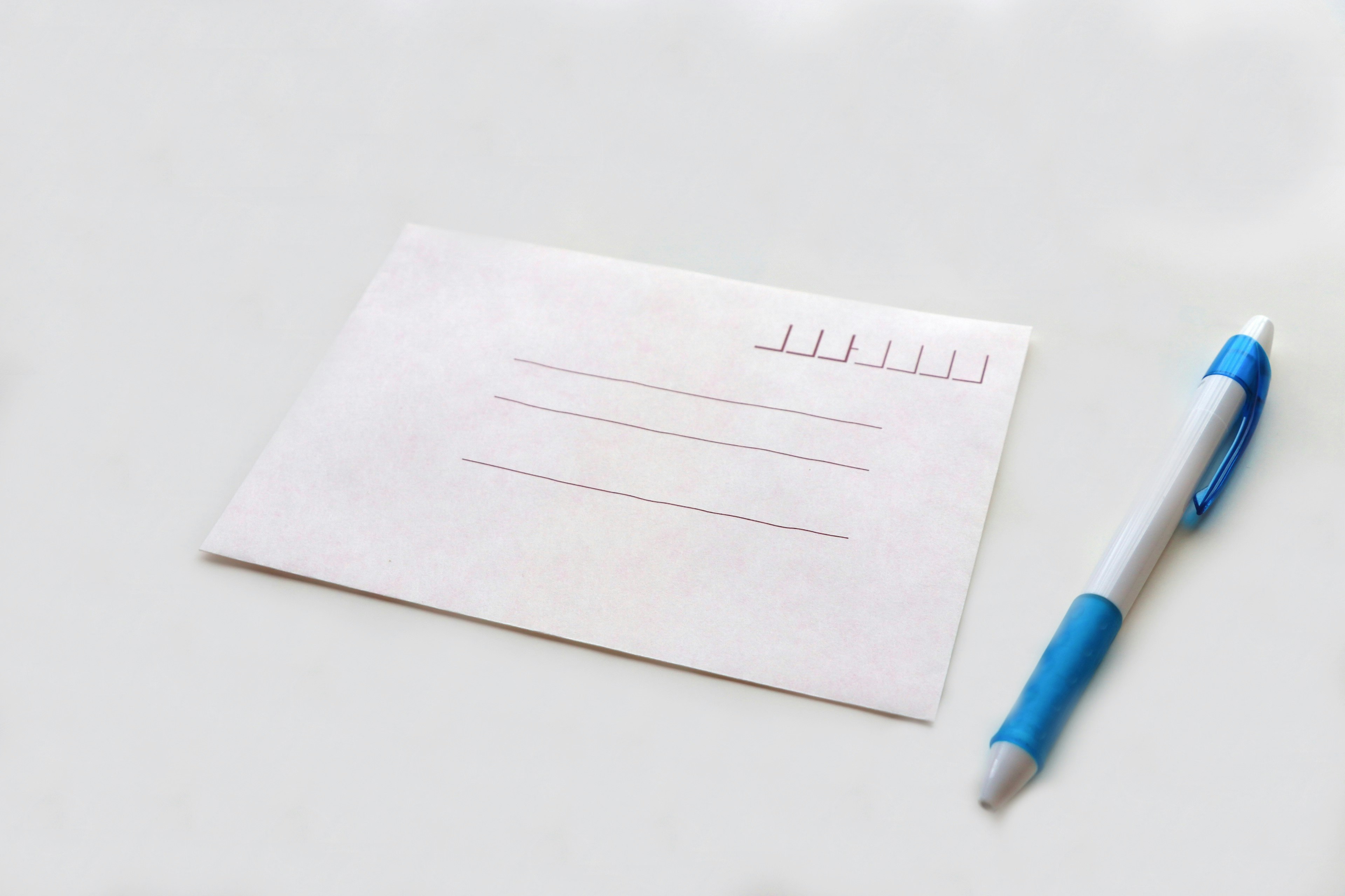 Une enveloppe blanche et un stylo bleu posés sur une table