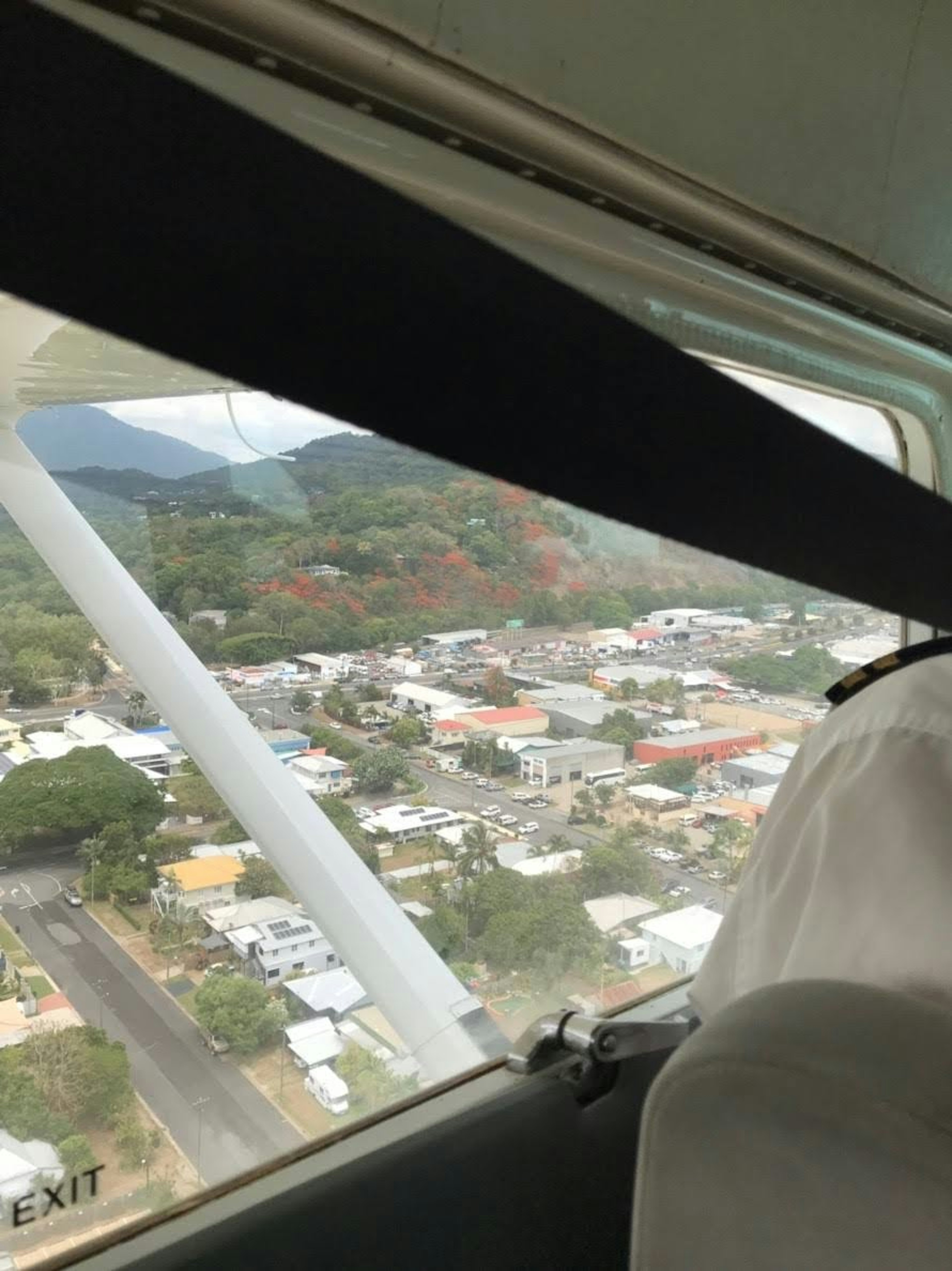 View from an airplane window showing a town and mountains