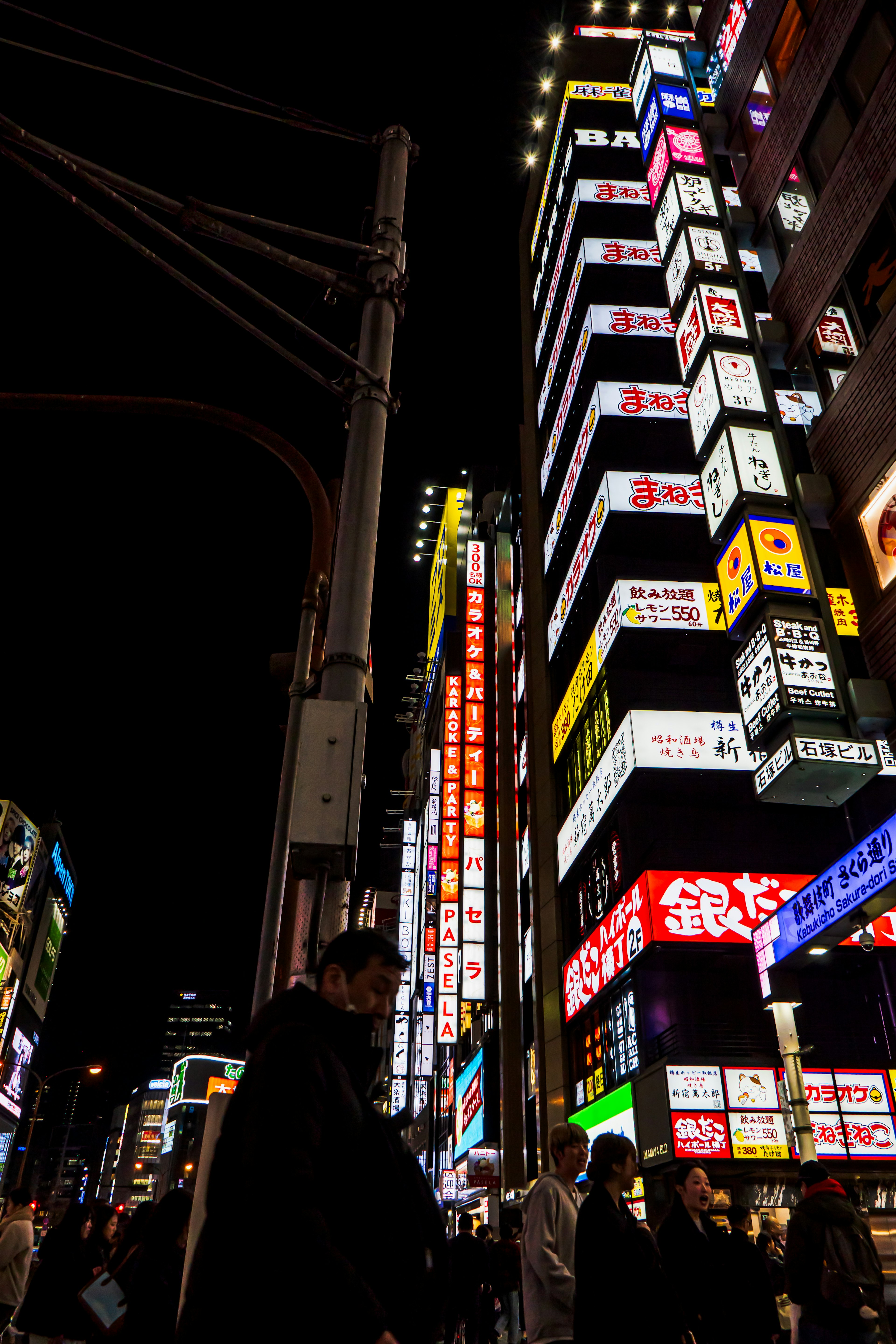 Insegne al neon vibranti che illuminano una strada cittadina di notte con silhouette di persone