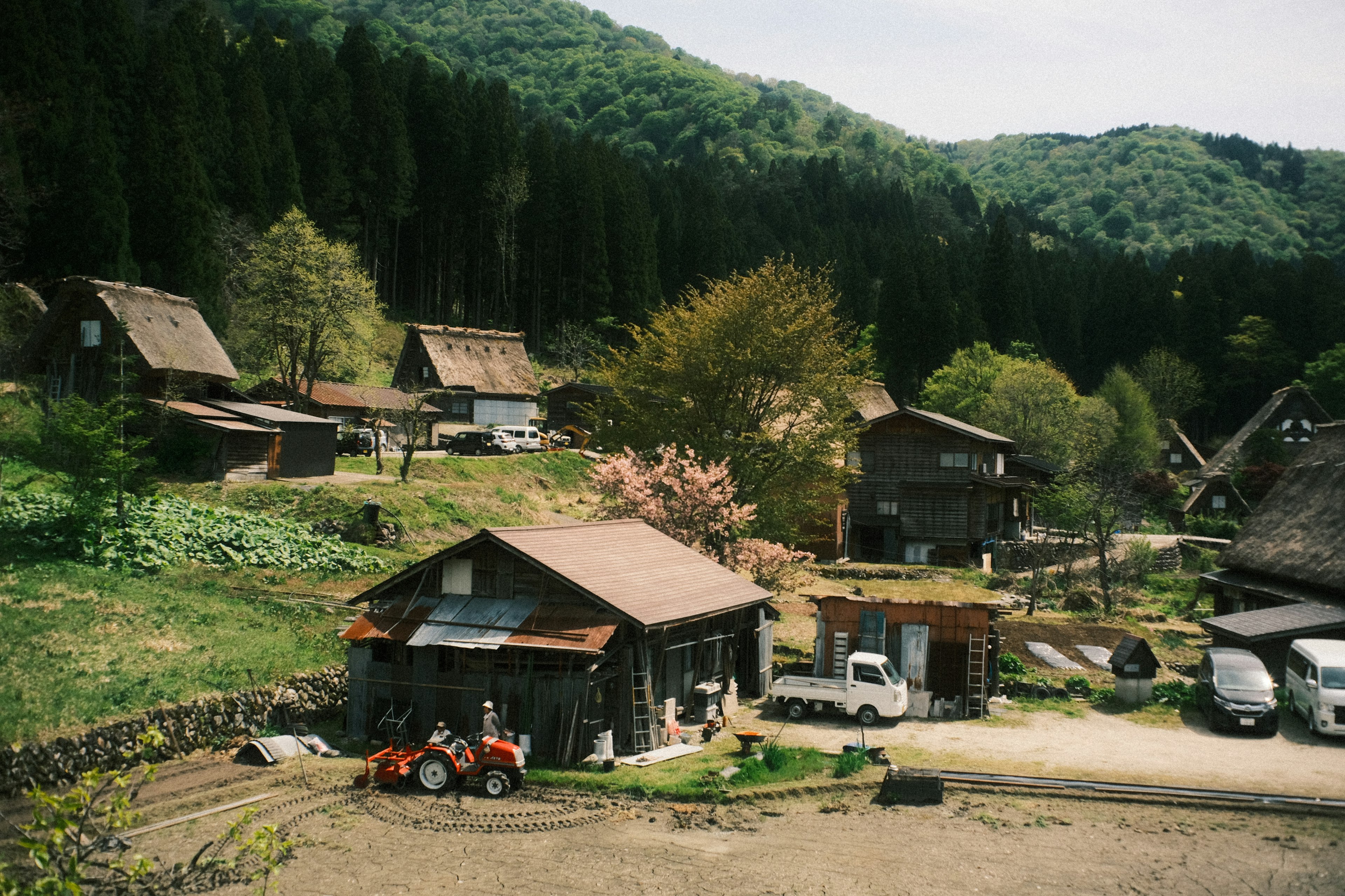 Traditional rural landscape surrounded by mountains featuring old houses and a tractor