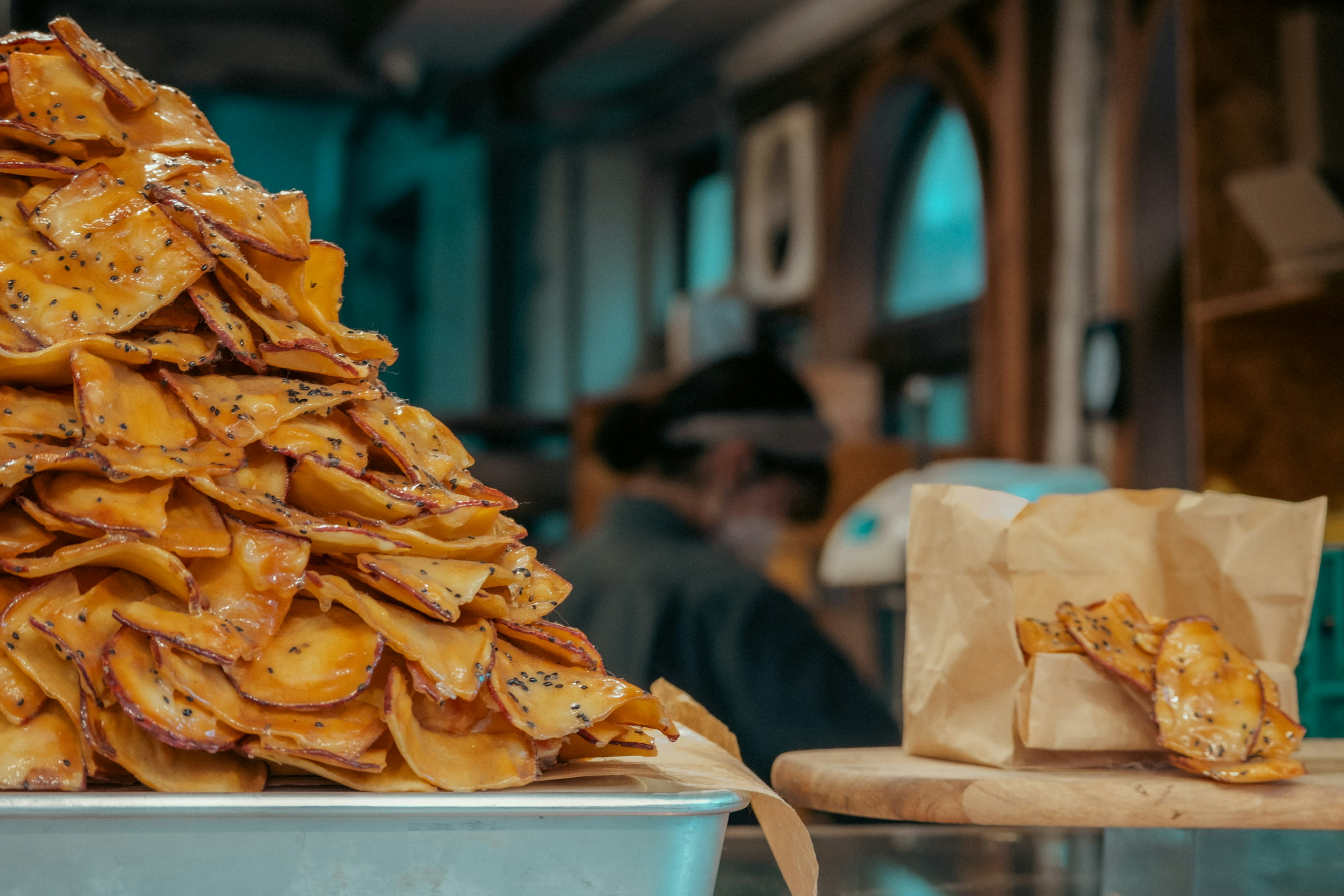 Una gran pila de chips de plátano fritas con un pequeño bocadillo envuelto sobre una mesa