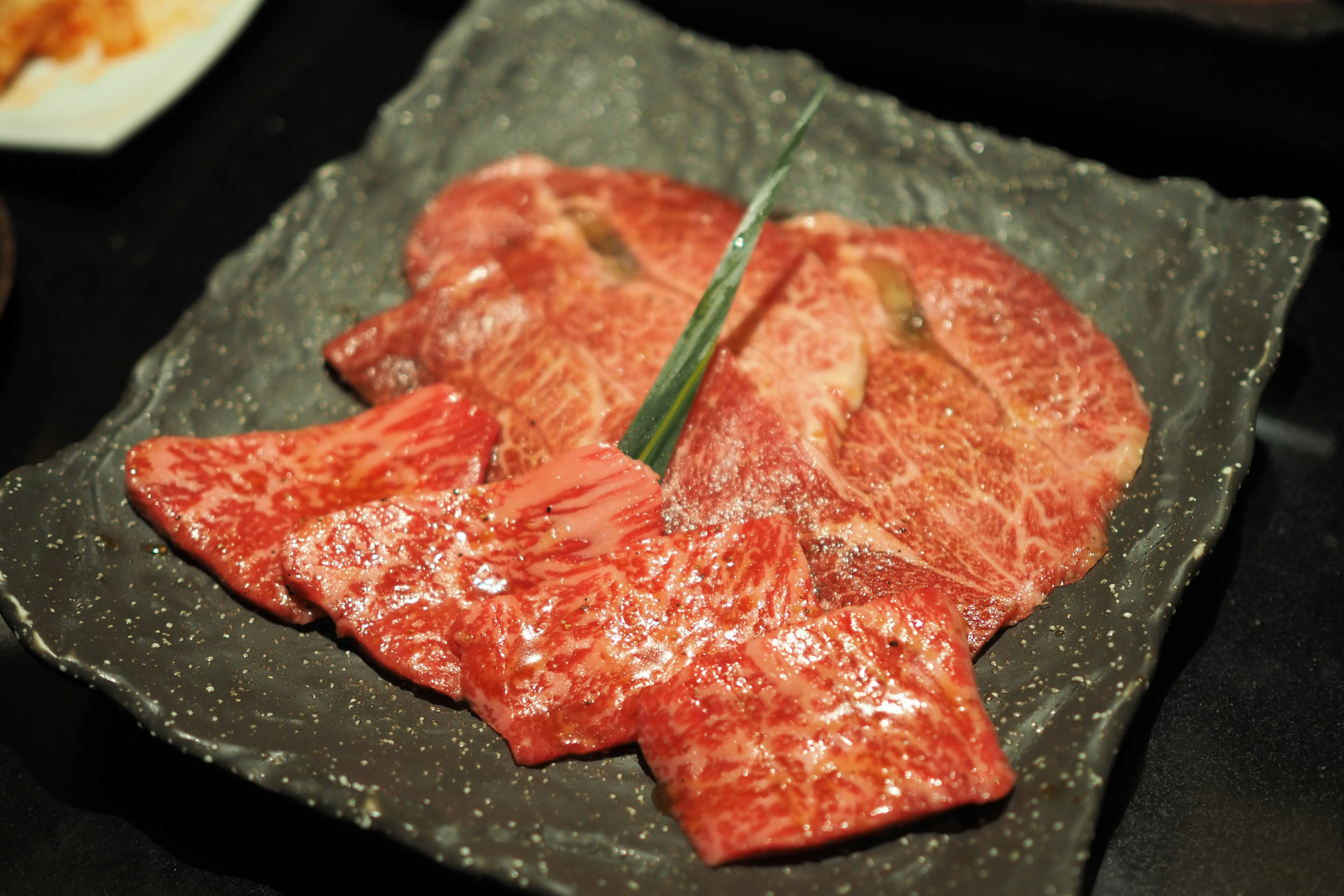 Carne en rodajas finas para barbacoa dispuesta en un plato negro