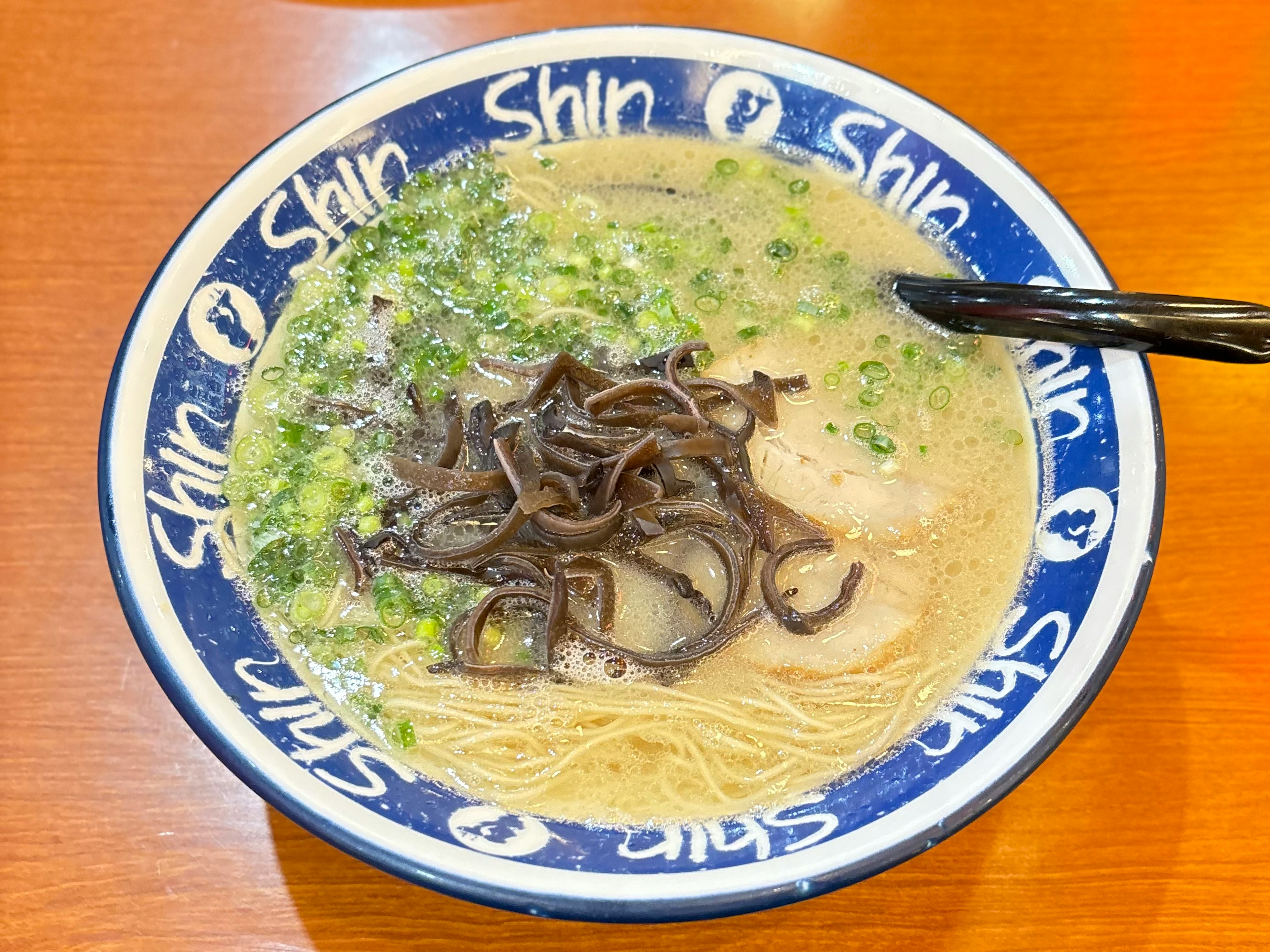 Ciotola di ramen Shin con noodles sottili, funghi neri e cipolle verdi in brodo ricco