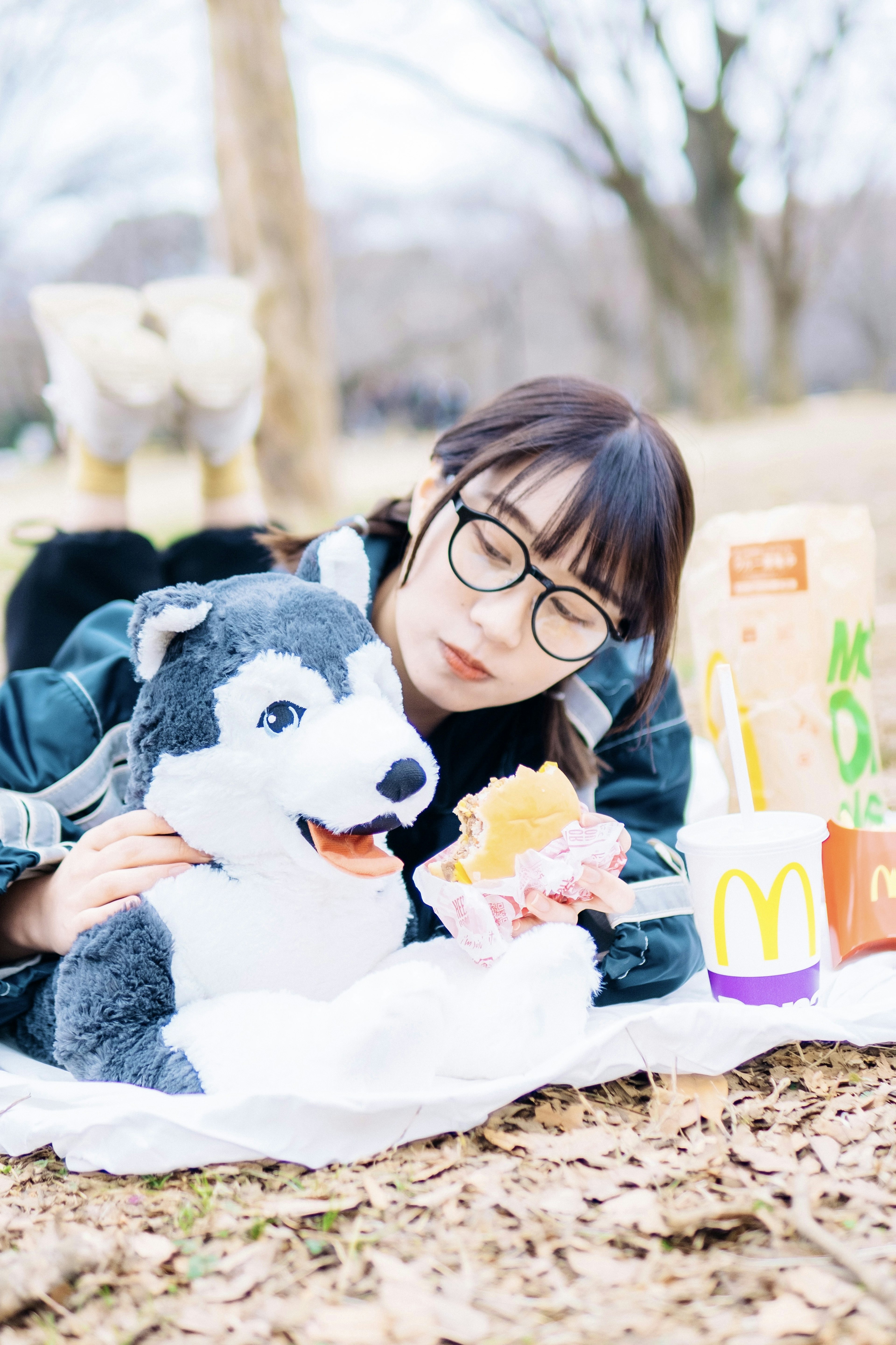 公園でぬいぐるみの犬と一緒に食事を楽しむ女性