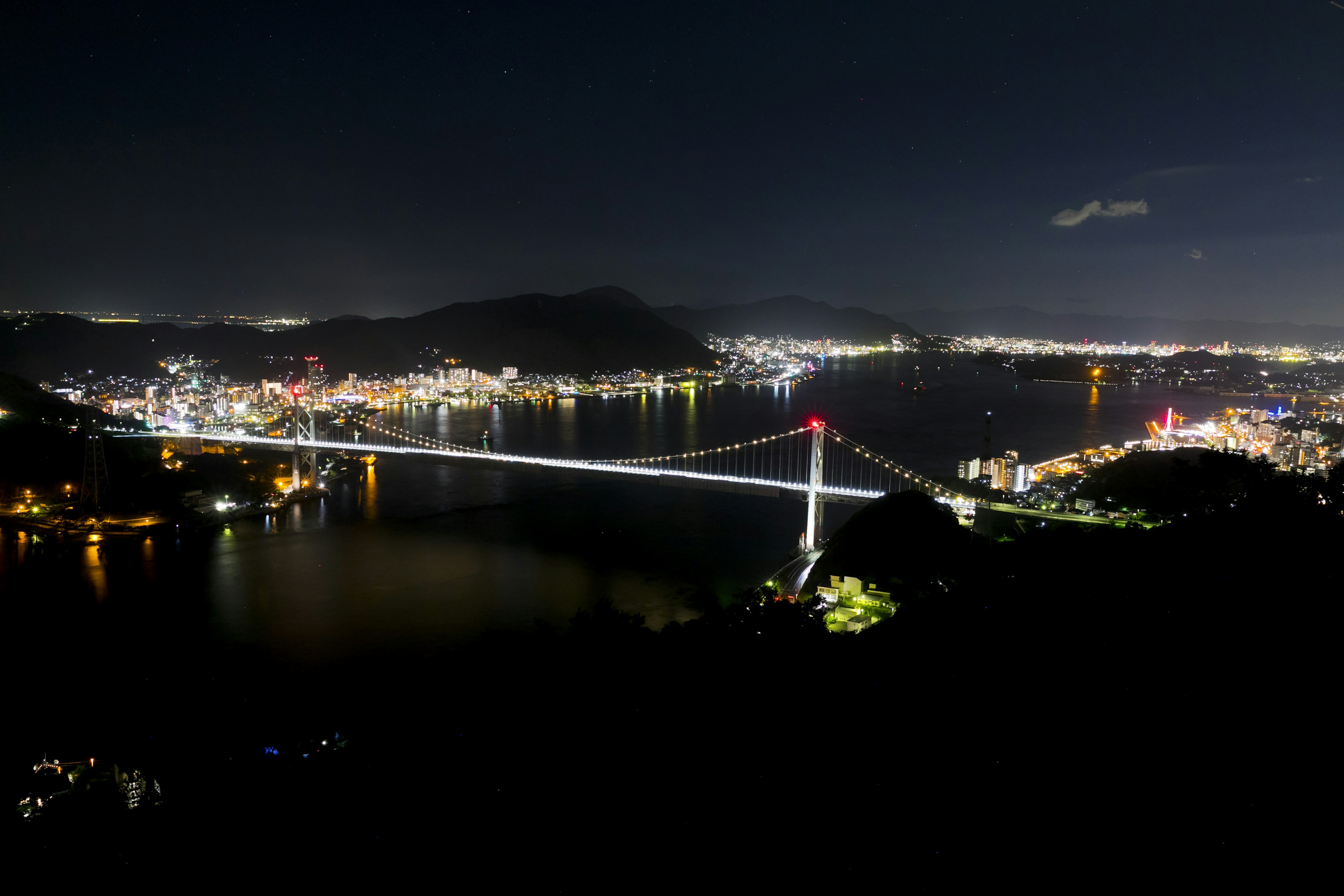 Jembatan yang diterangi dan lampu kota di malam hari