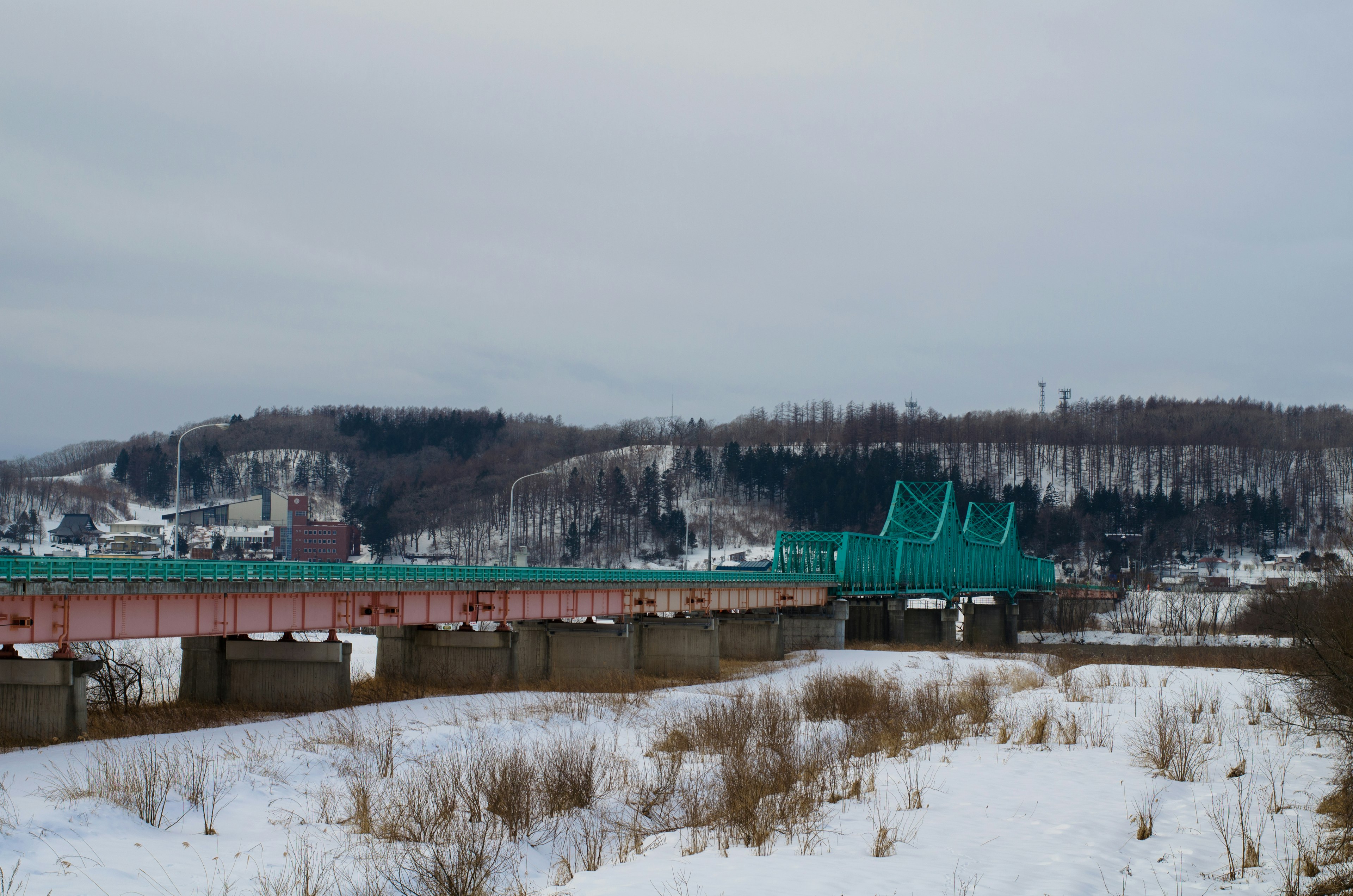 Pont bleu sur un paysage enneigé avec des collines en arrière-plan