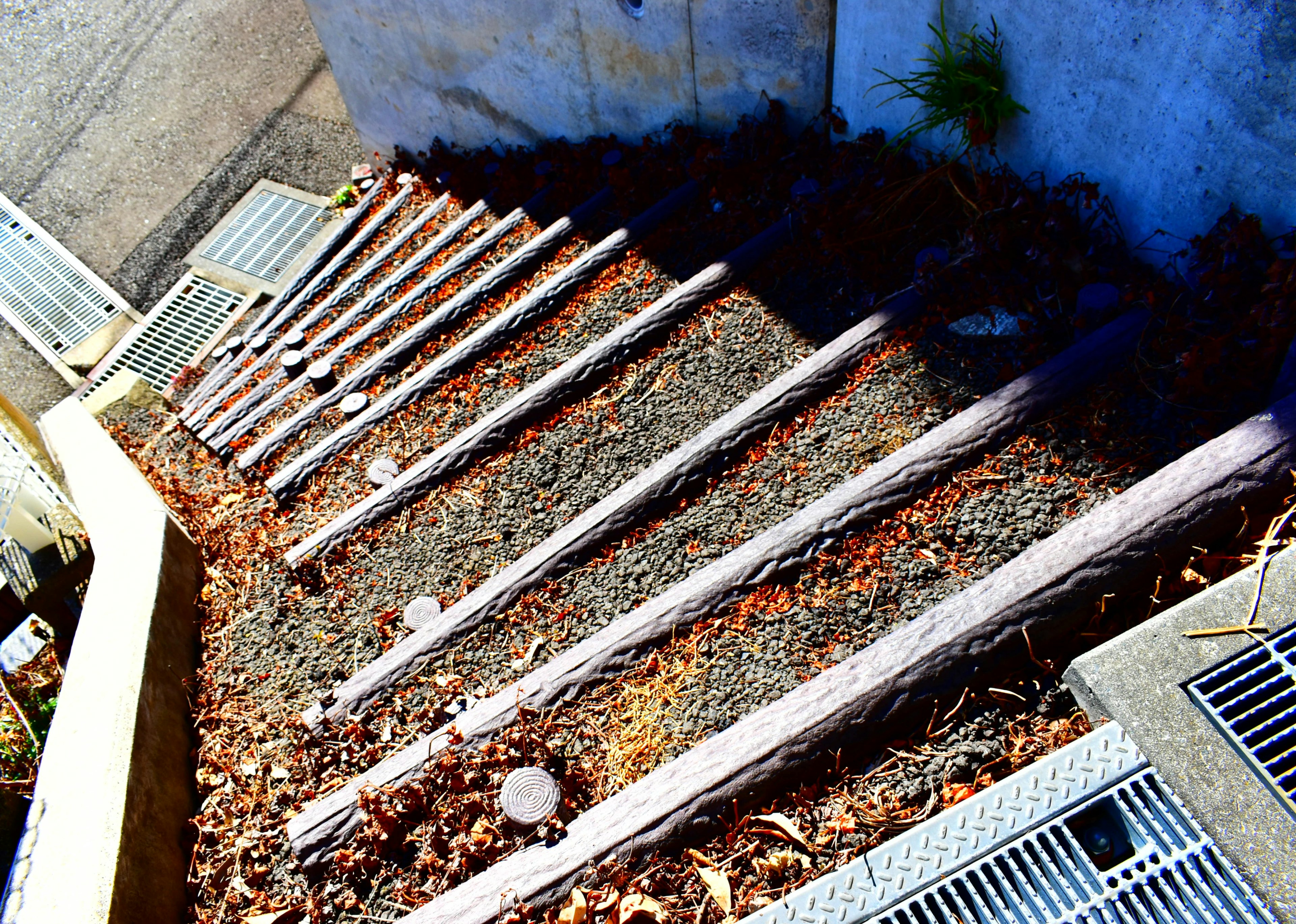 Image de bûches en bois disposées comme des escaliers avec un sol en gravier