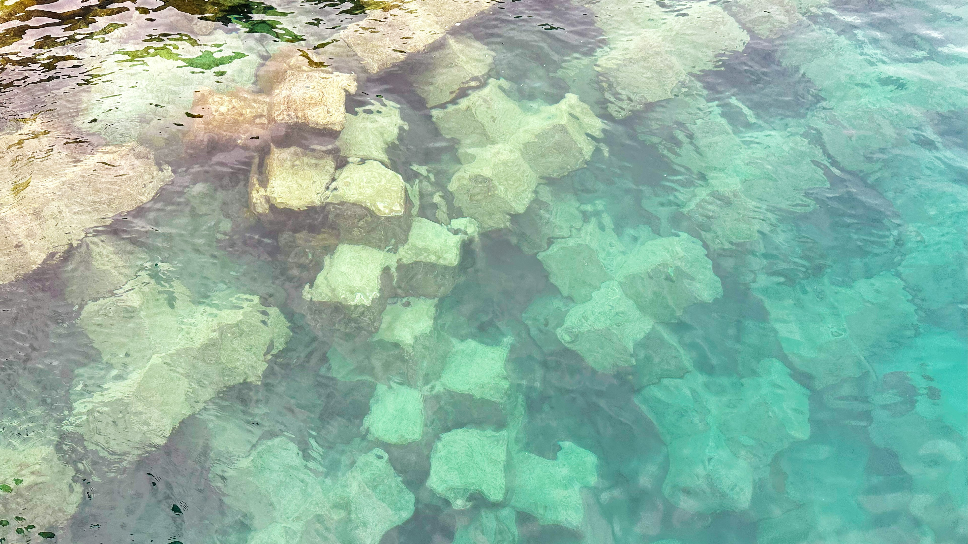 Underwater stone structures visible through clear water