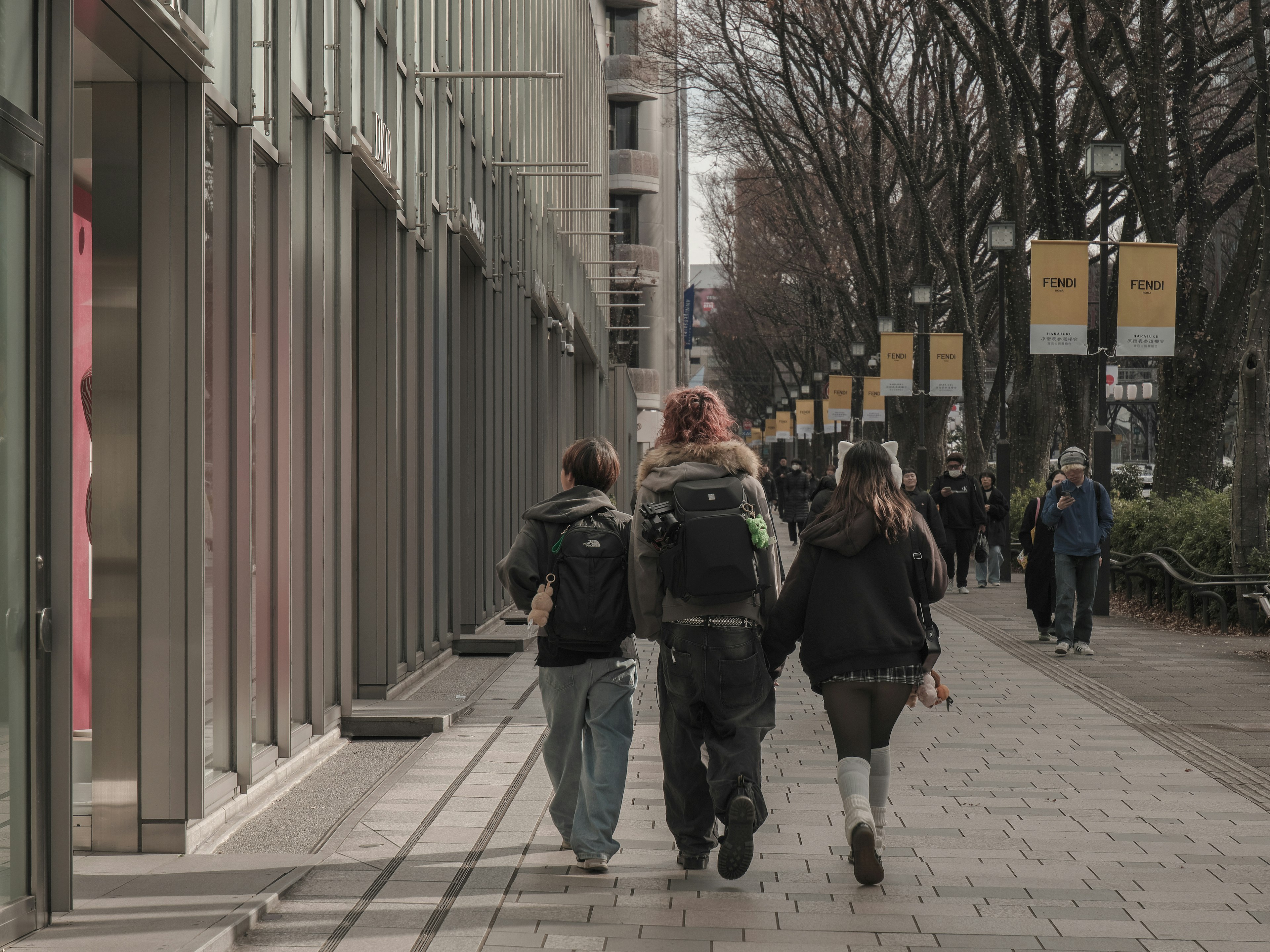 人們在城市環境中行走，街道旁邊有商店櫥窗和樹木