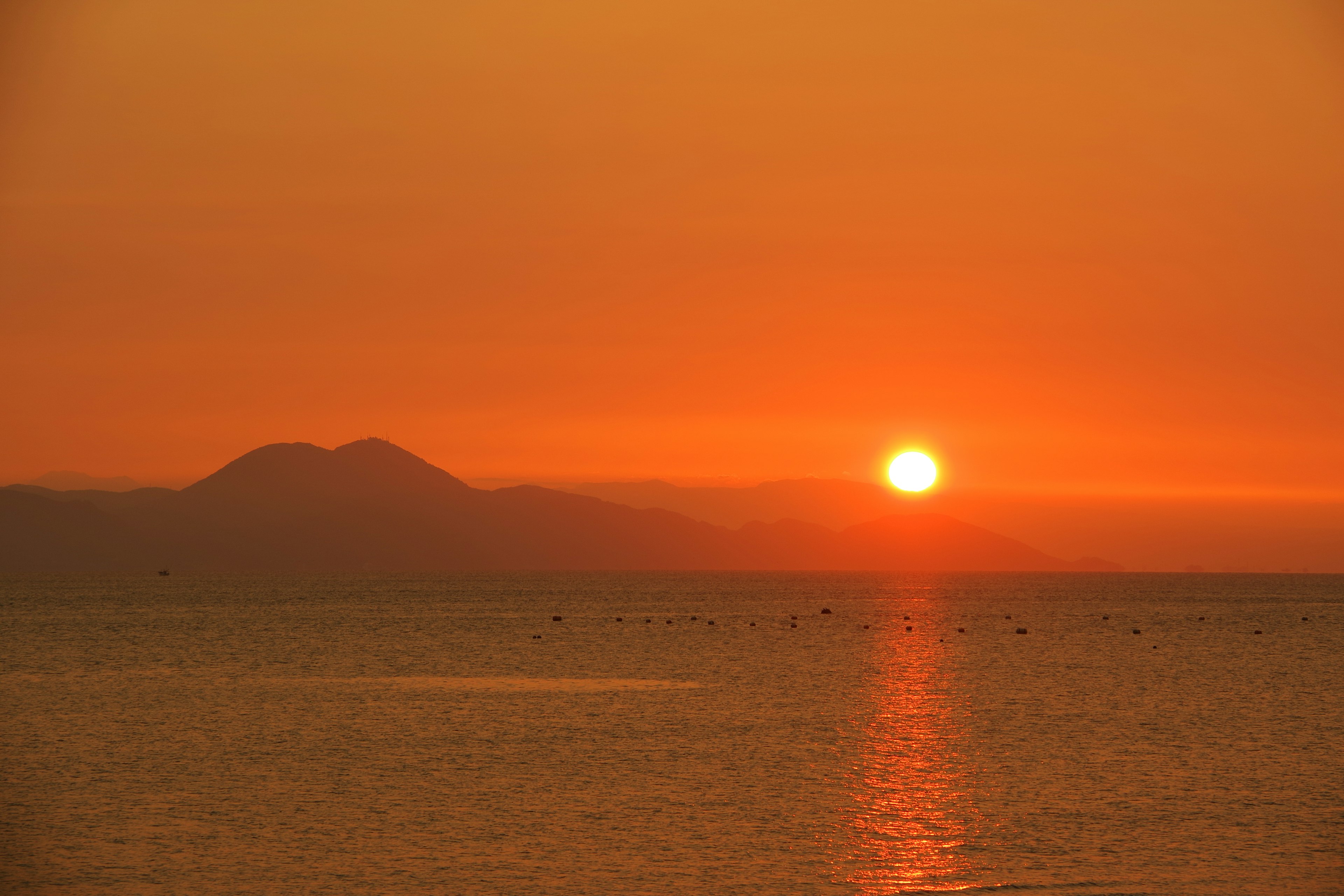 Bellissimo tramonto arancione sul mare con montagne lontane