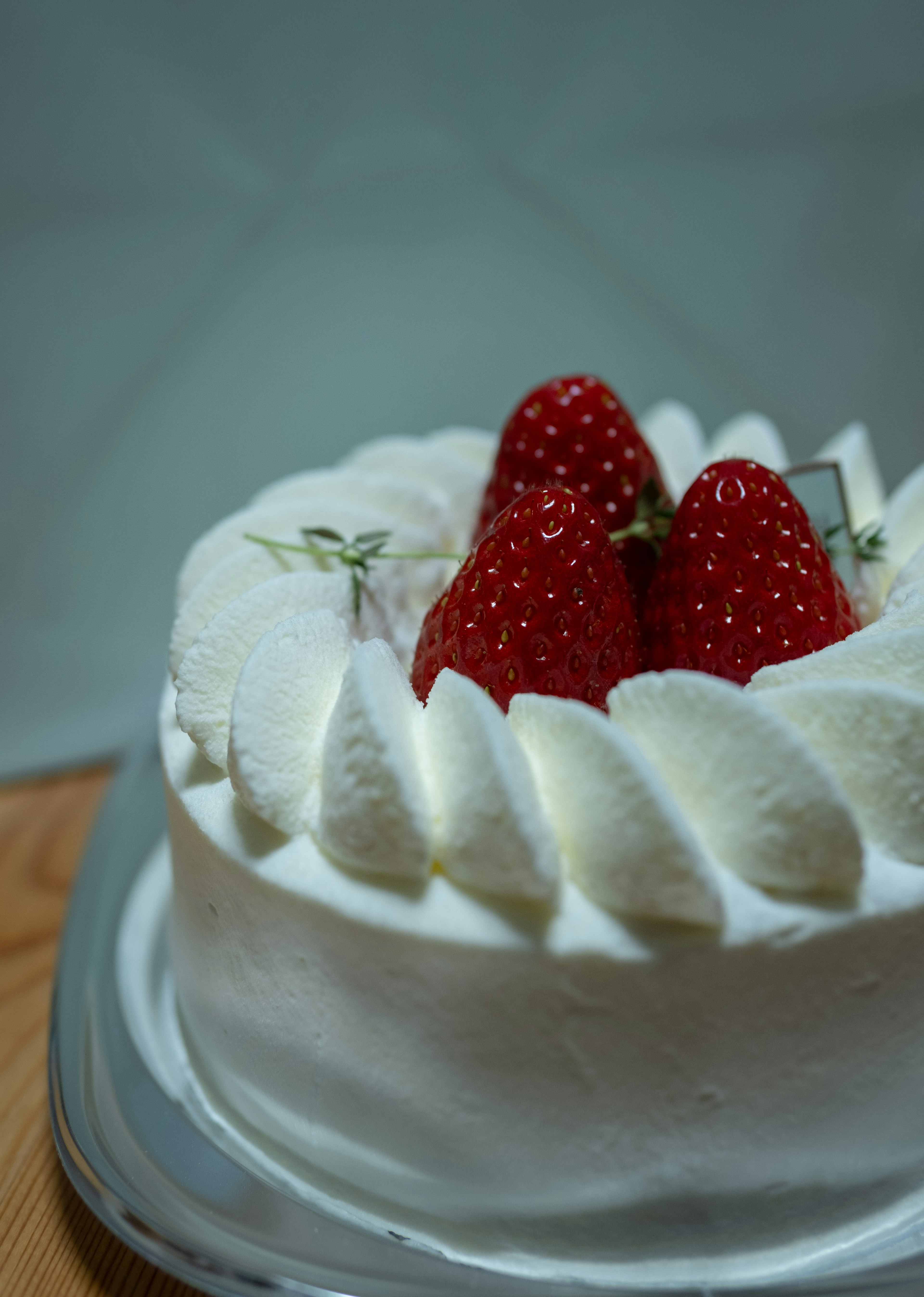 Gâteau à la crème aux fraises surmonté de trois fraises fraîches