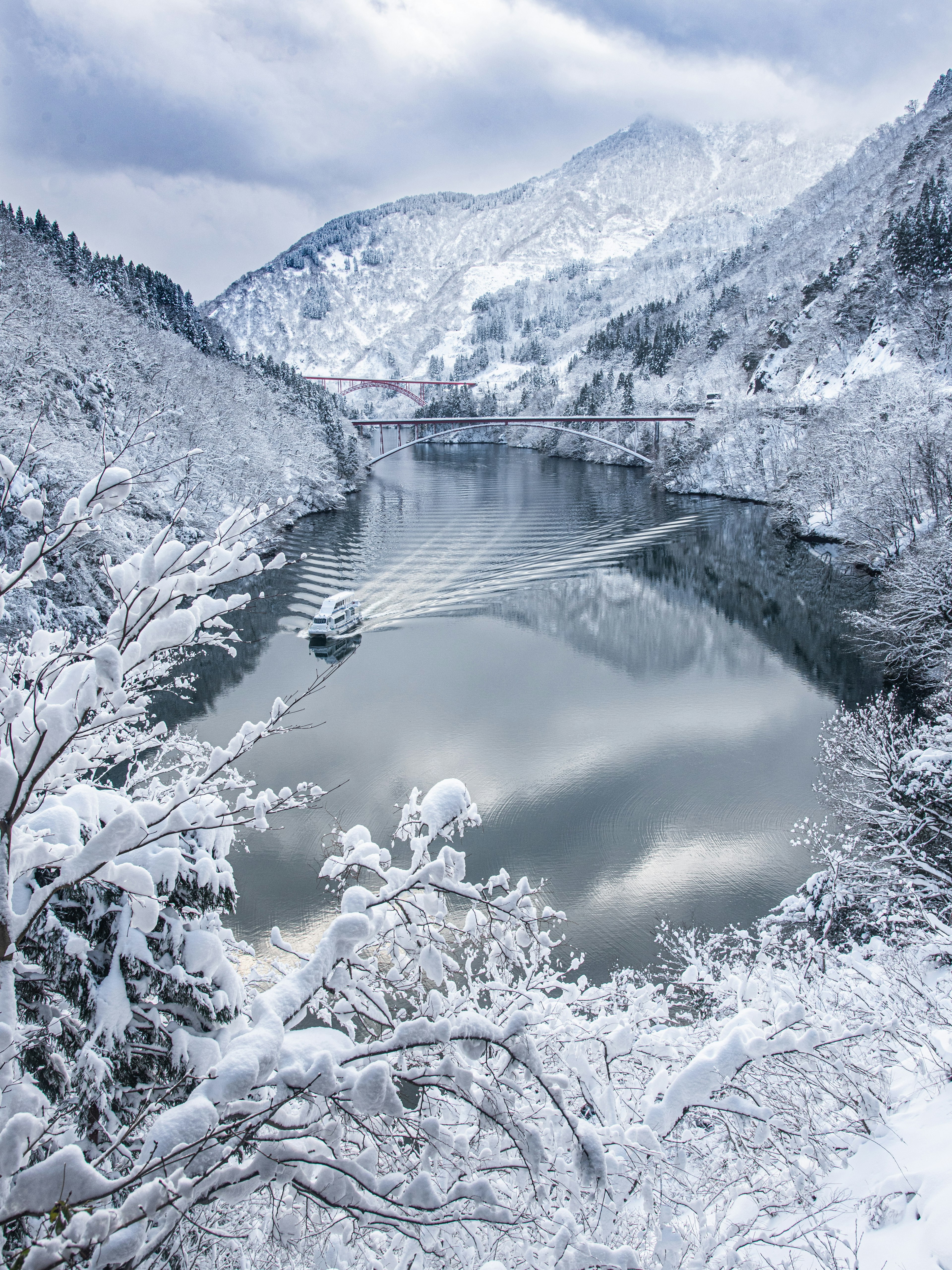 Wunderschöne verschneite Landschaft mit Bergen und Fluss ein Boot gleitet über das ruhige Wasser