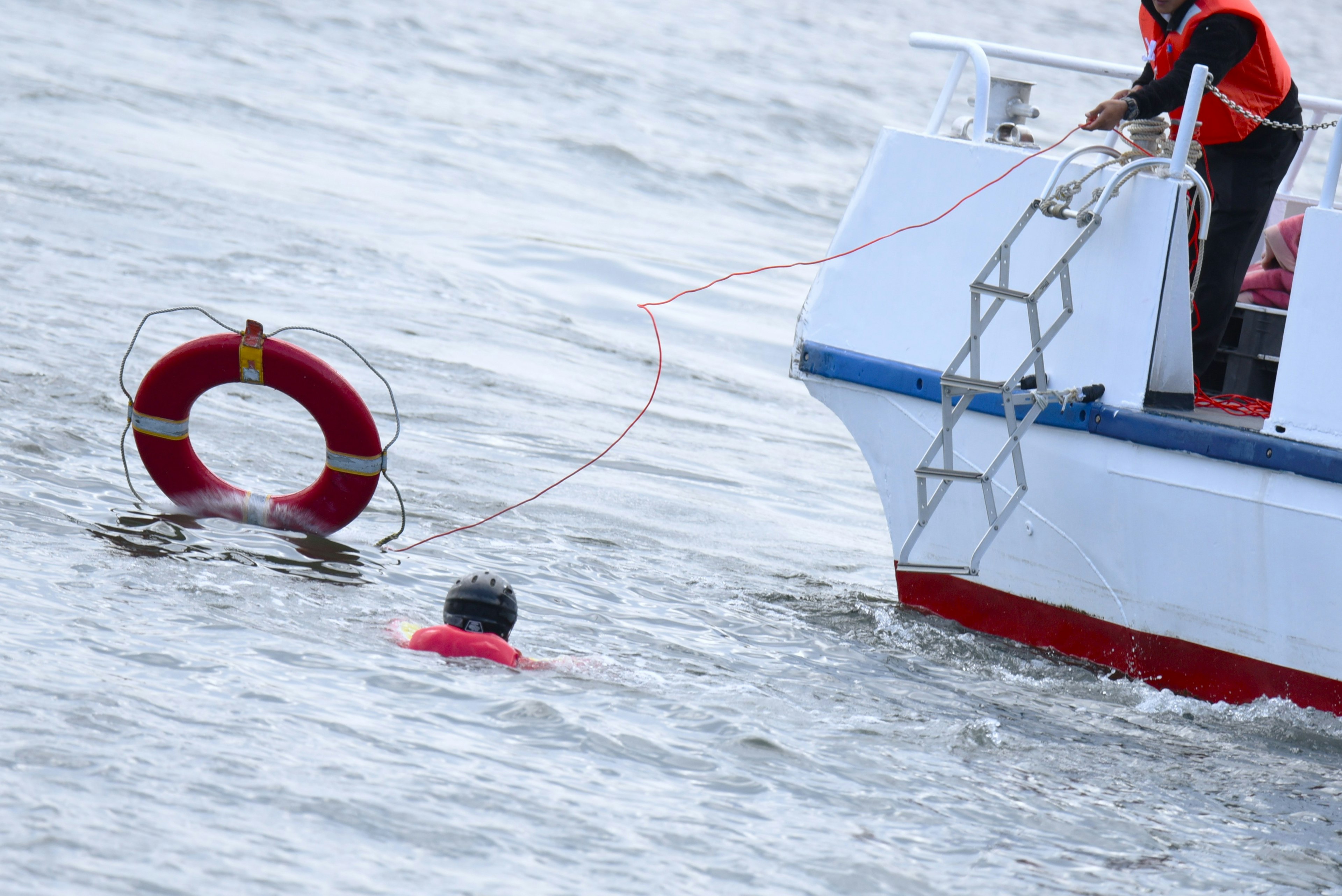 A person in the water near a boat with a lifebuoy