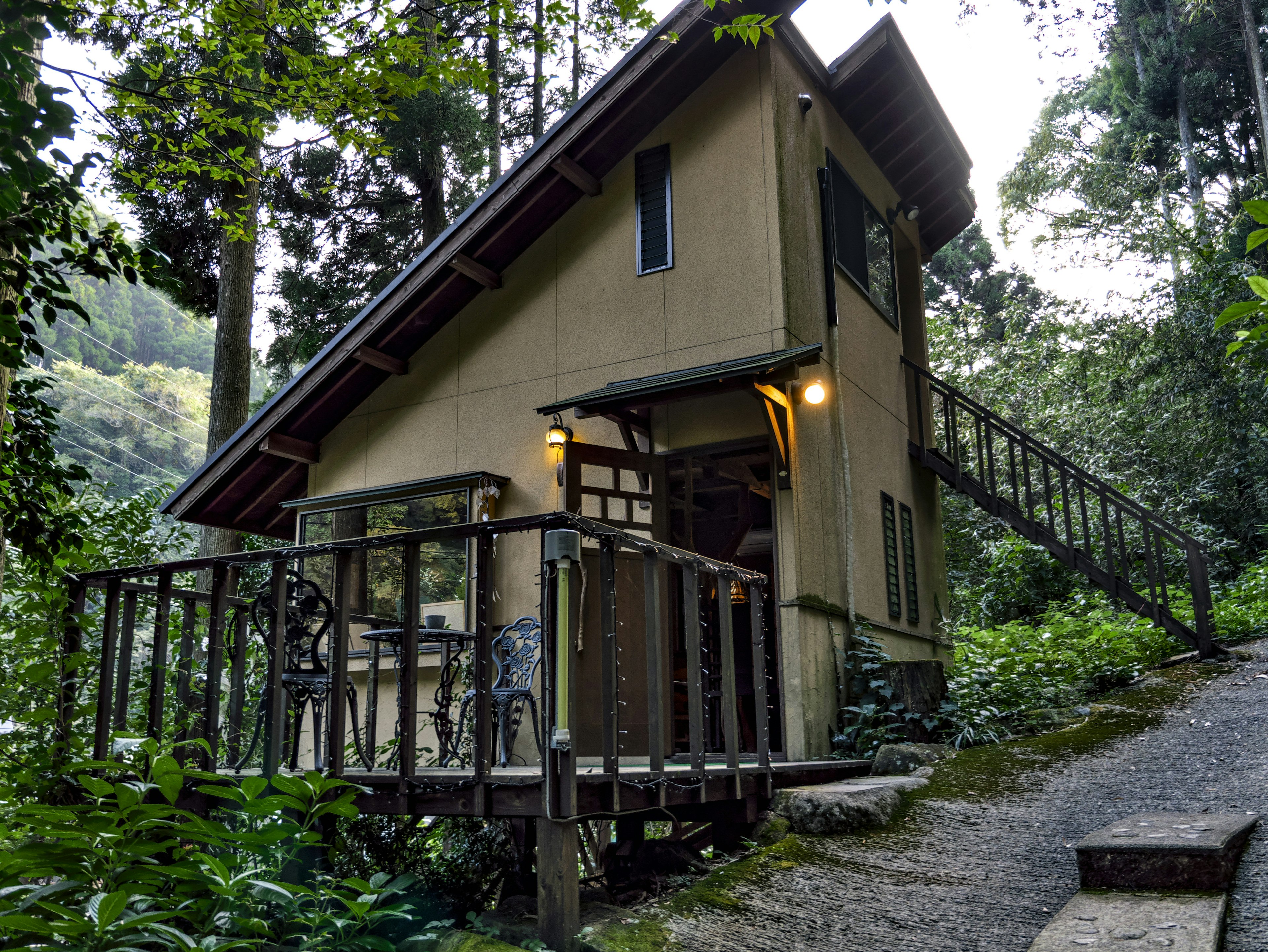 Small house in the forest featuring a wooden deck and stairs