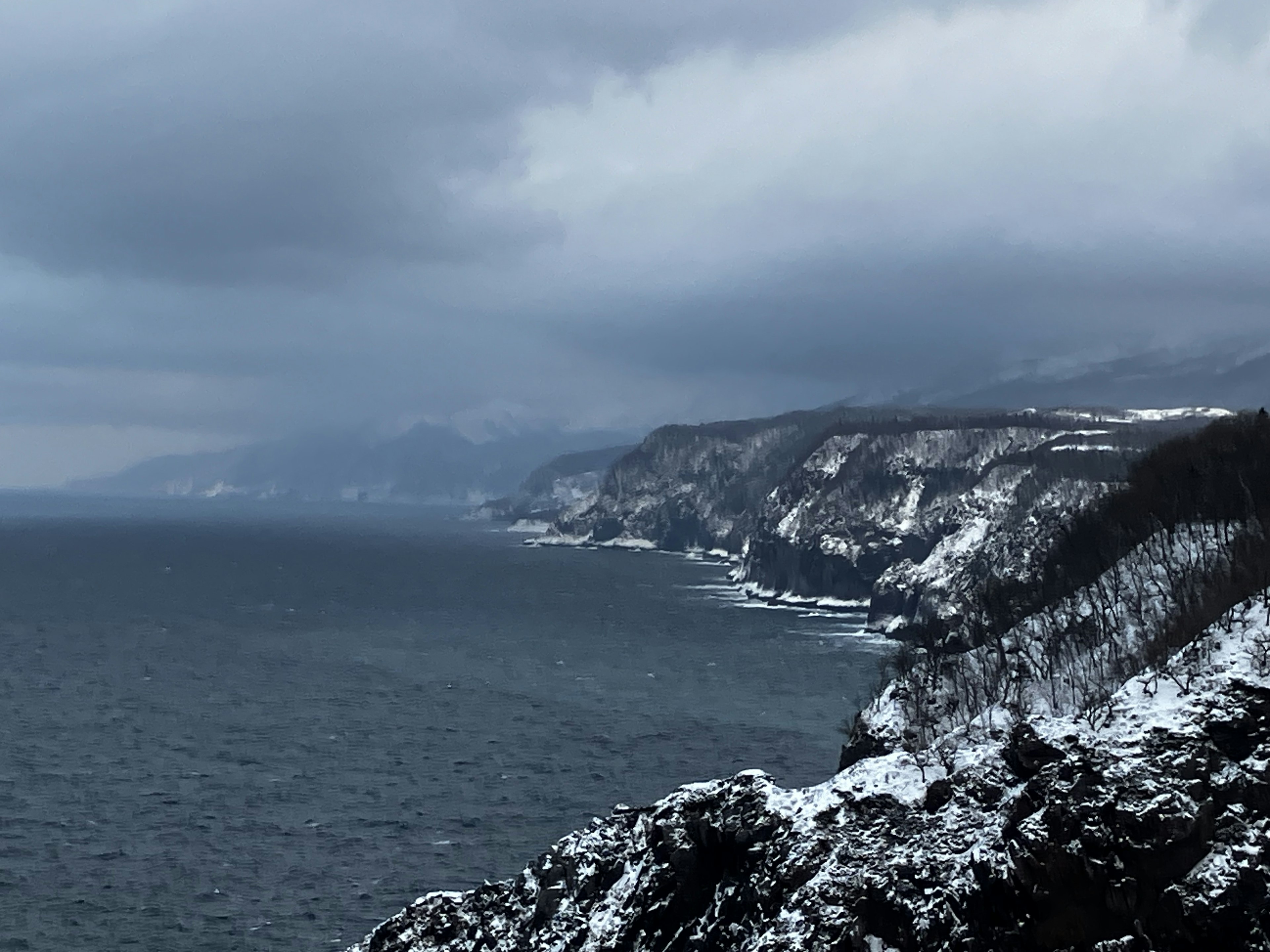 雪に覆われた海岸線と暗い雲が広がる風景