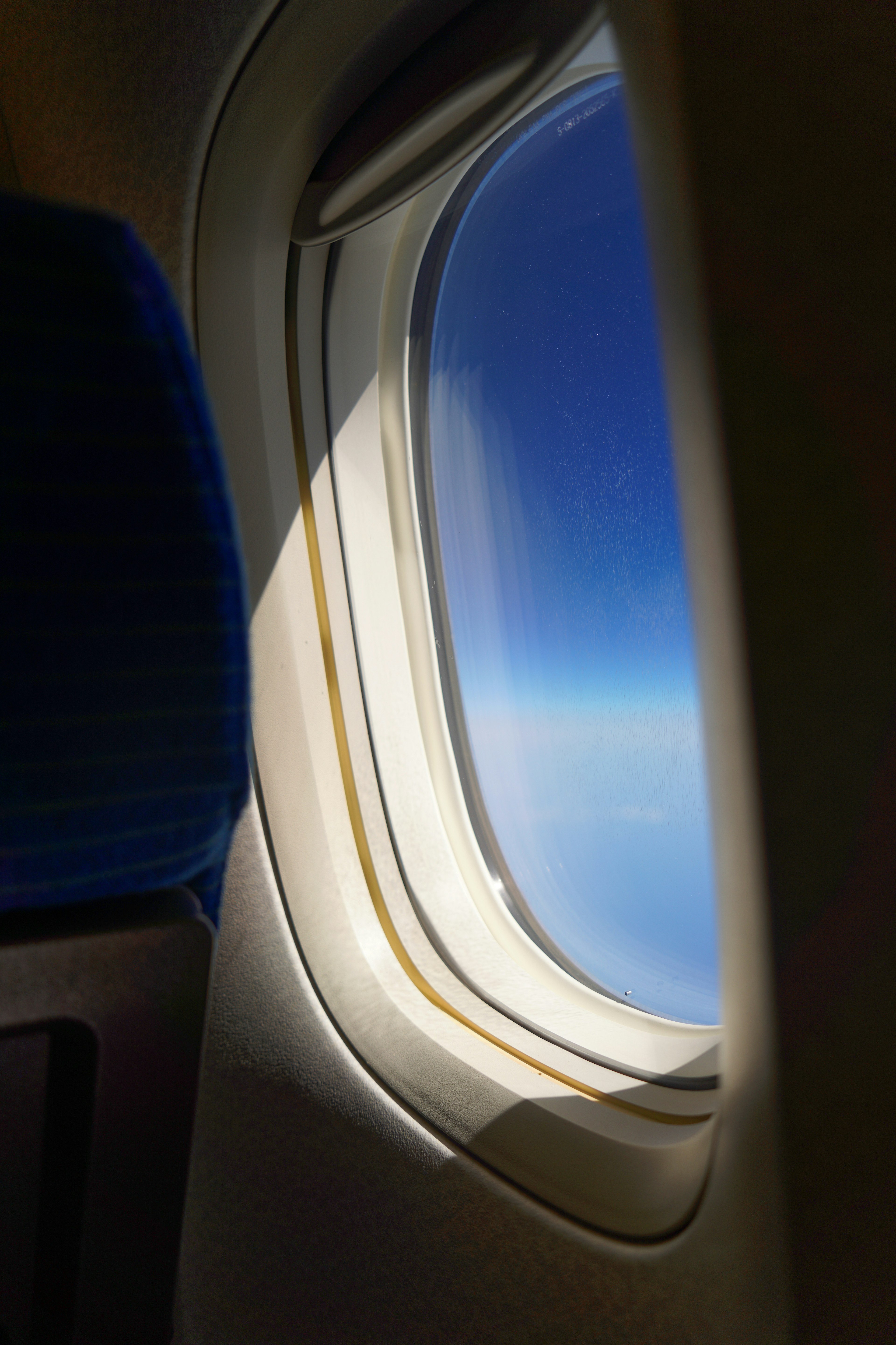 View of clear blue sky and clouds through an airplane window