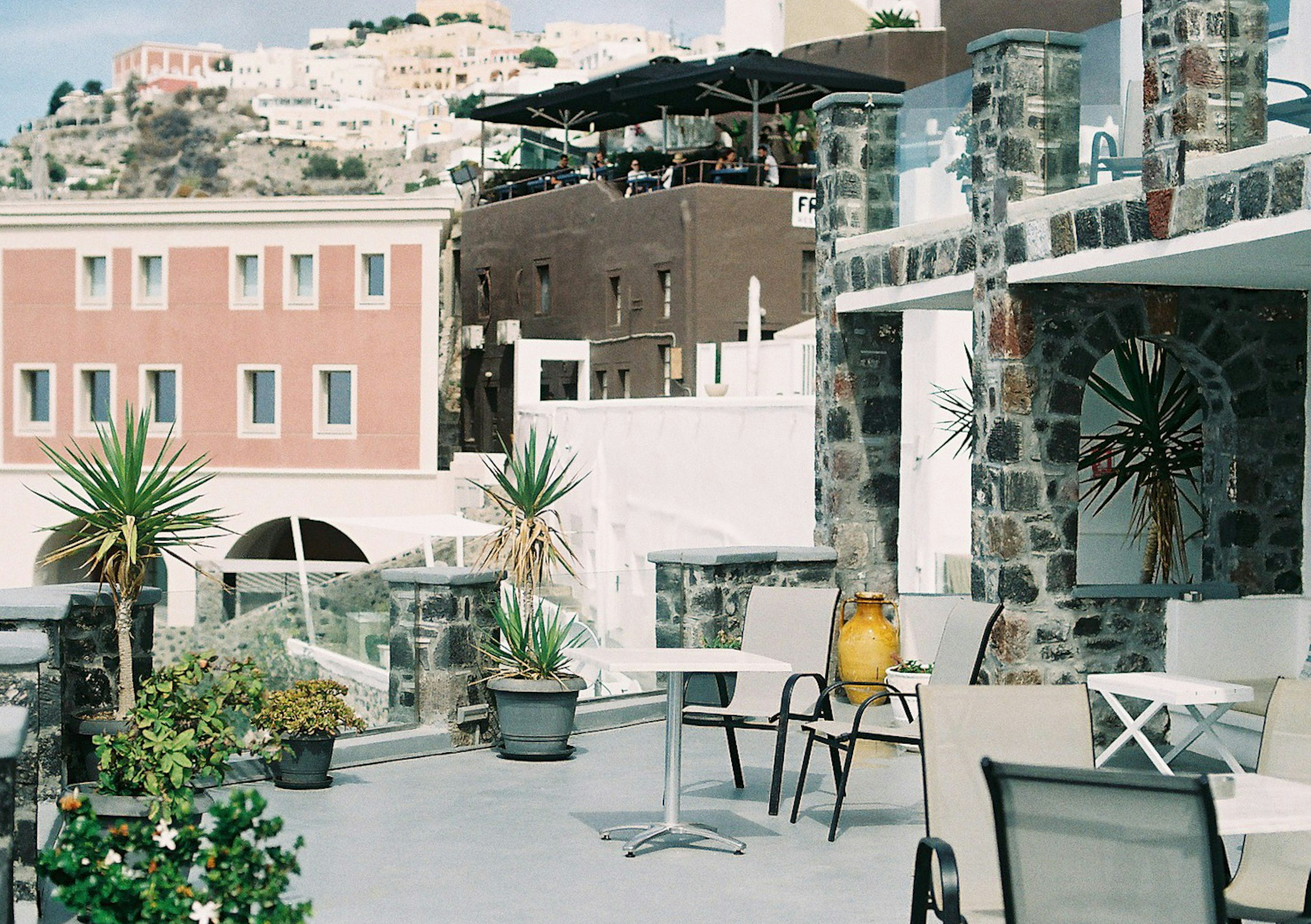 Schöne Terrasse mit Blick auf steinerne Gebäude, Pflanzen, Tische und Stühle