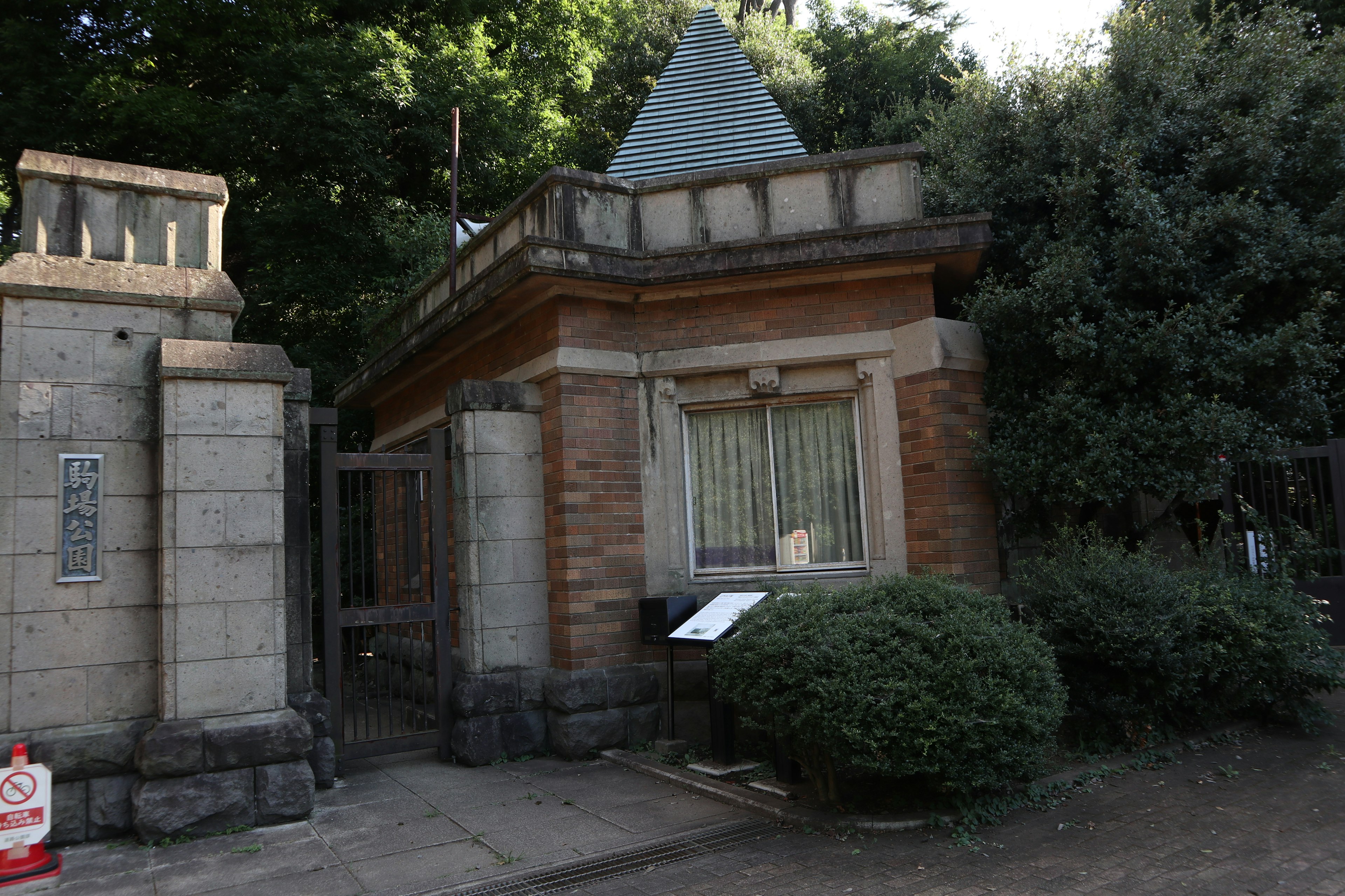 Entrance of an old building surrounded by greenery featuring a pyramid-shaped roof