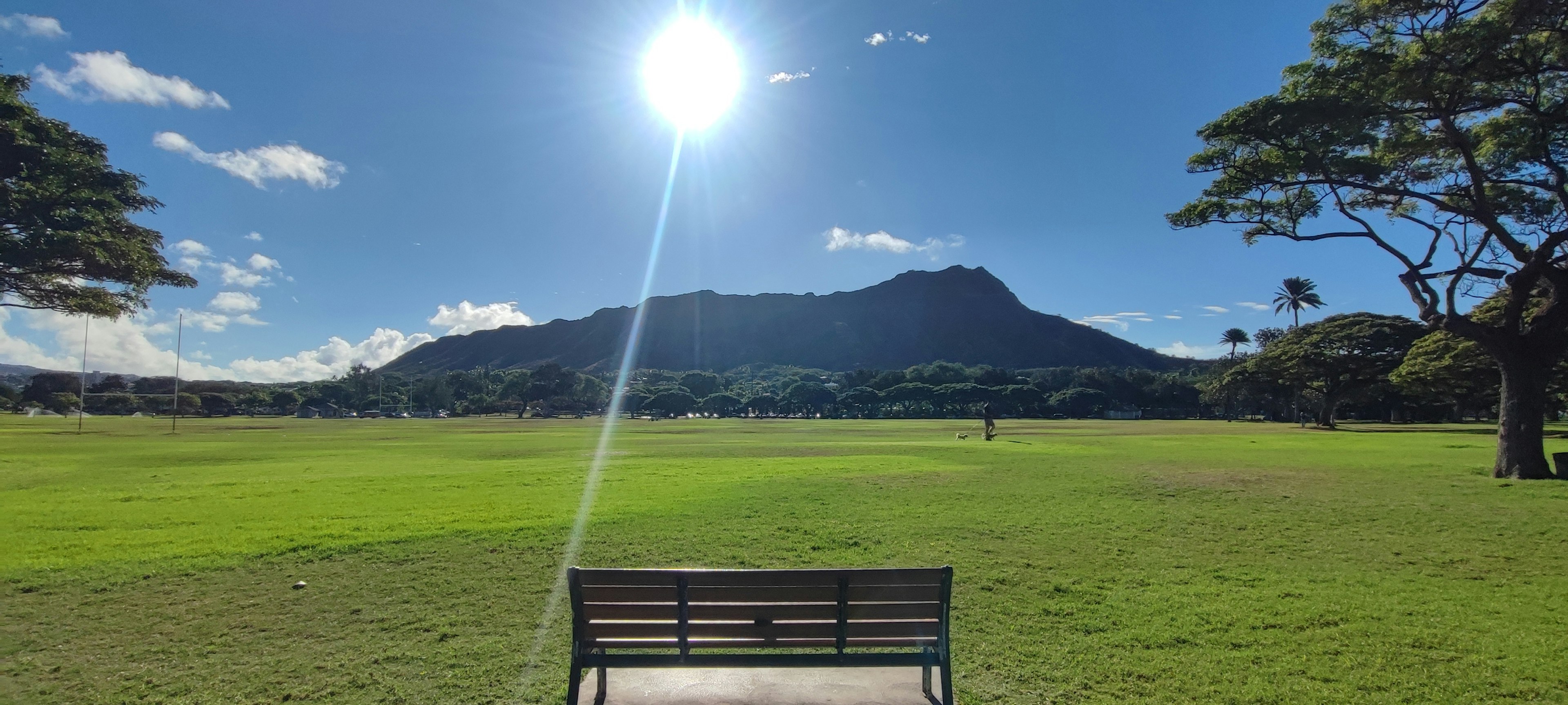 Park bench overlooking a mountain landscape with bright sun and clear sky